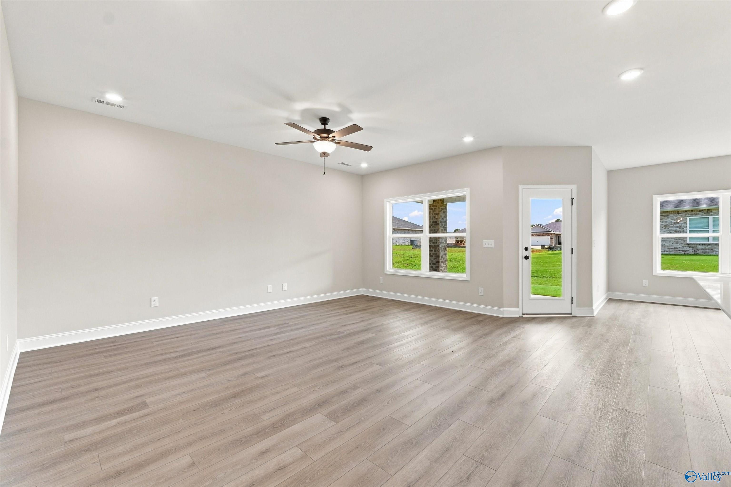 Bright open-concept living room with luxury vinyl plank floors and backyard access in Davidson Homes Everett B, Toney, Alabama