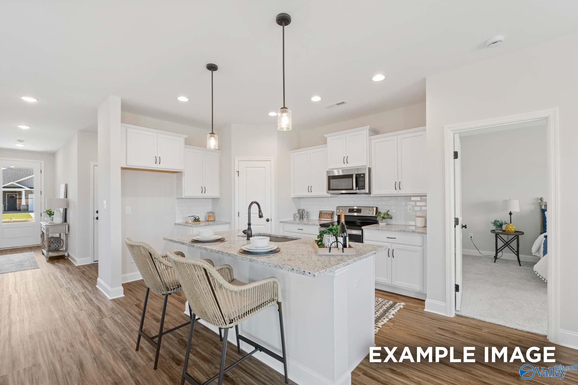 Modern kitchen with white cabinets, granite island, and bar seating in The Franklin C floor plan, Jaguar Hills, Huntsville.
