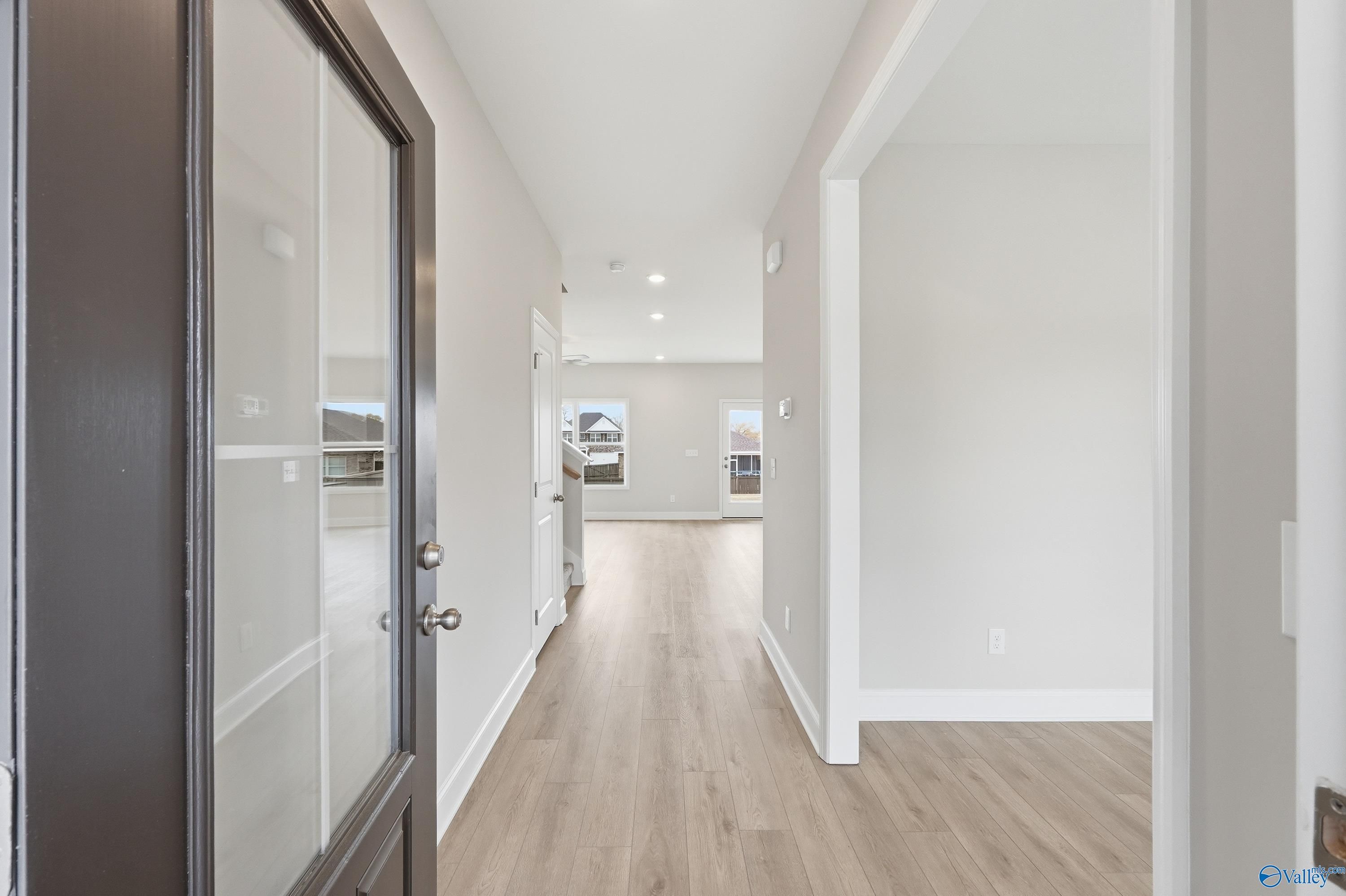Bright entry foyer with glass-paneled black door, light oak floors, and open hallway in Davidson Homes Shelby B, New Market, Alabama