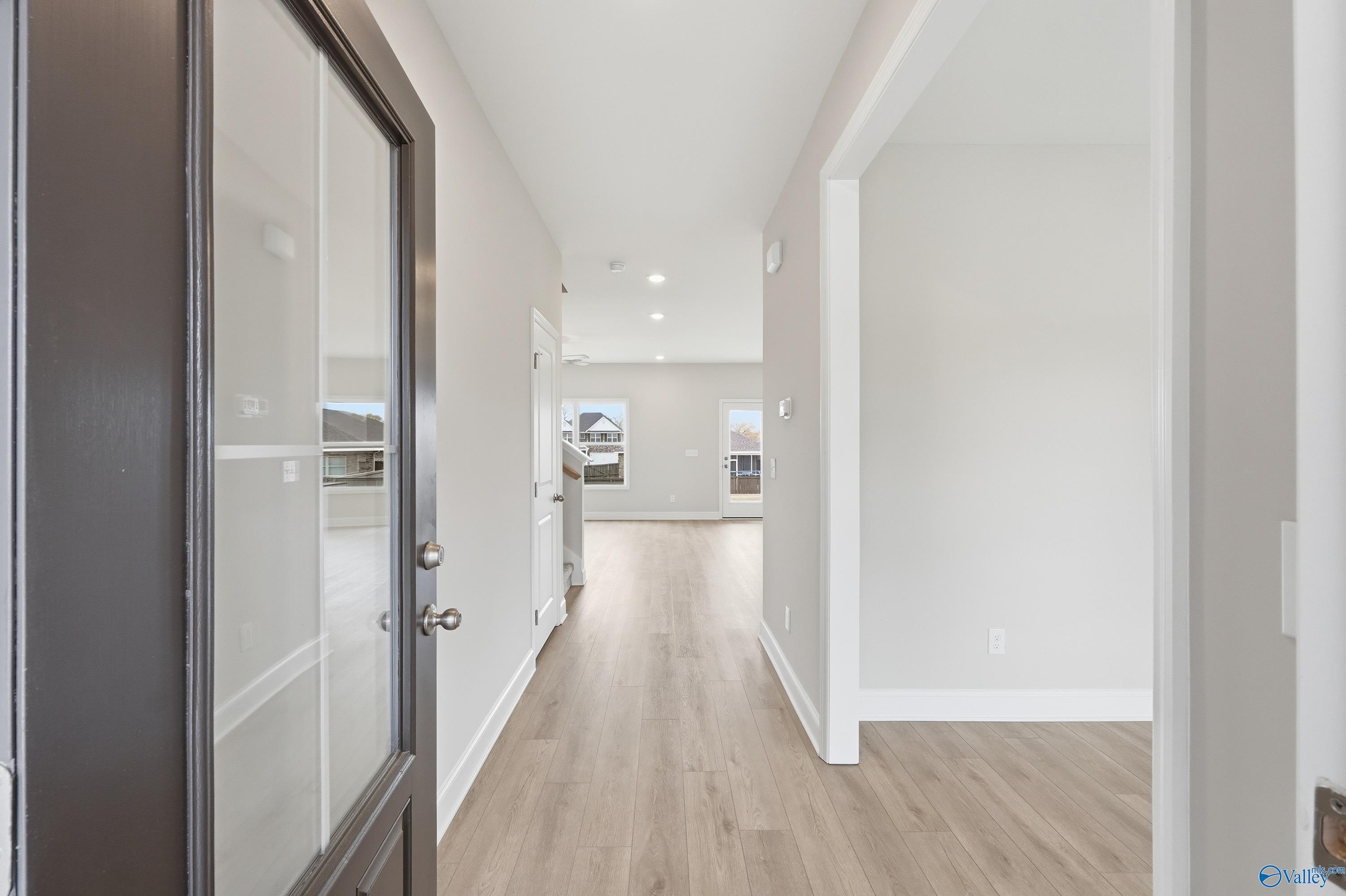 Bright entry foyer with glass-paneled black door, light oak floors, and open hallway in Davidson Homes Shelby B, New Market, Alabama