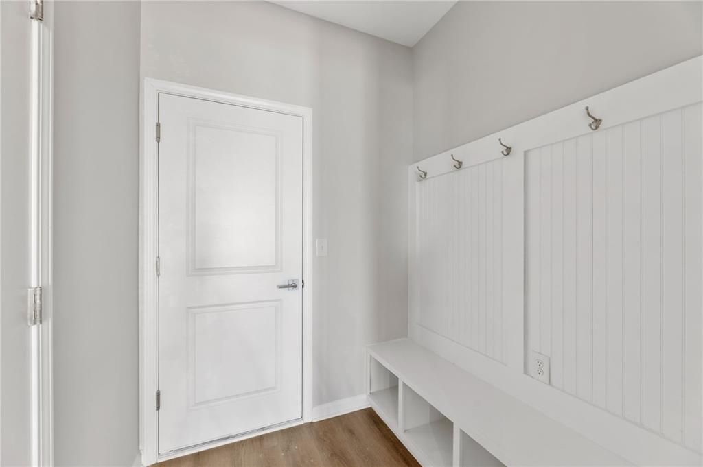 Functional mudroom with white shiplap lockers, bench, and hooks beside door in Davidson Homes The Marion A, Winder, Georgia