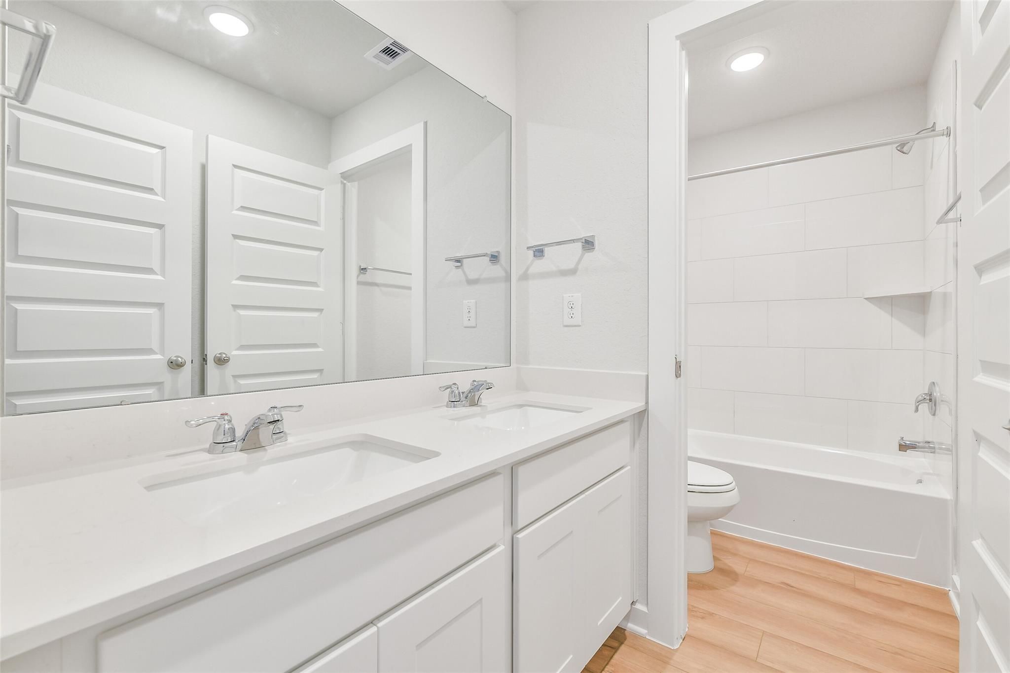 Bright bathroom featuring double vanity, white cabinetry, bathtub, and recessed lighting in The Blanco E 4-bedroom home, Magnolia, Texas