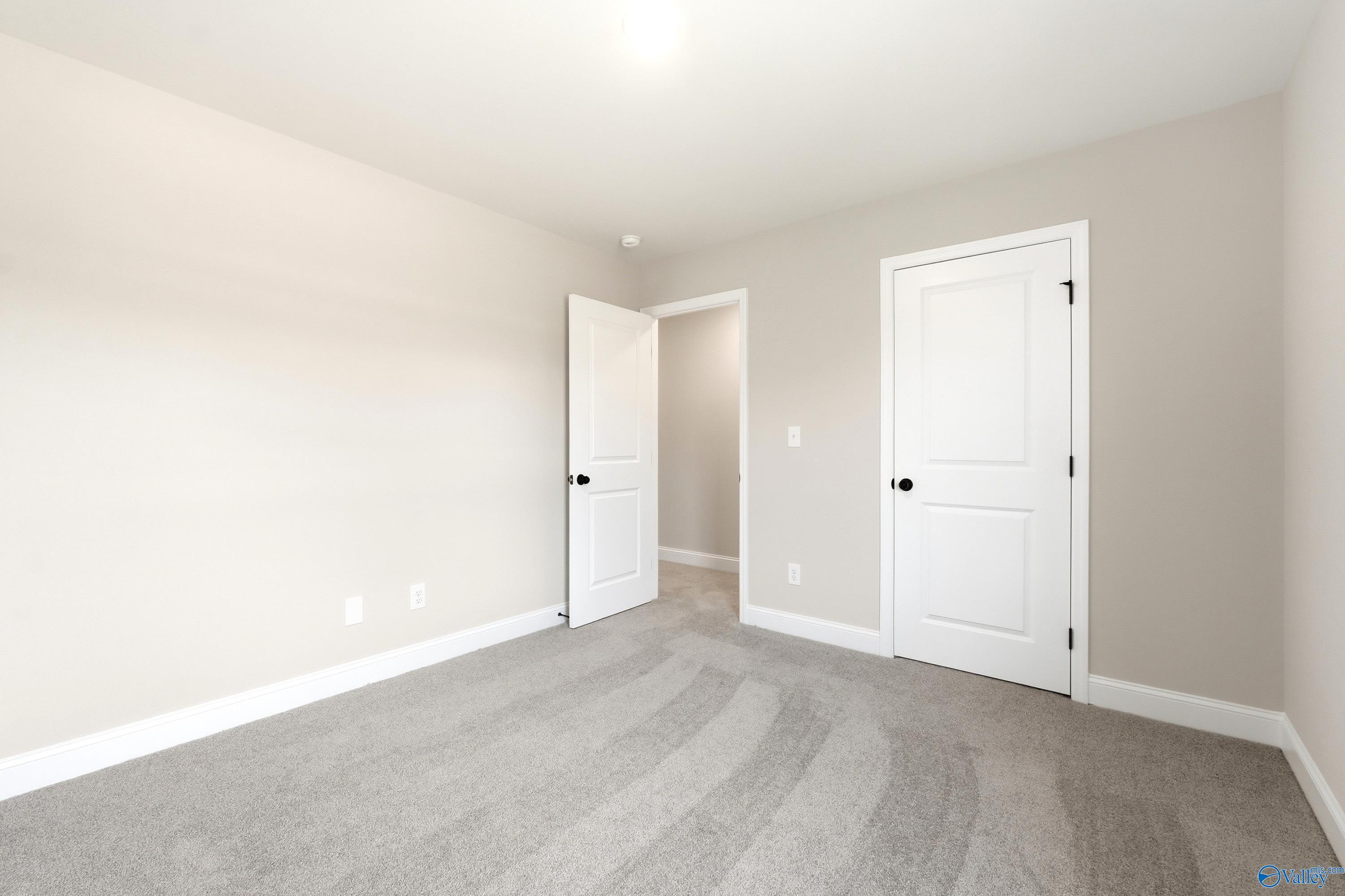 Bright bedroom with neutral walls and plush carpeting in a Davidson Homes Russell A floor plan in Spragins Cove, Huntsville.