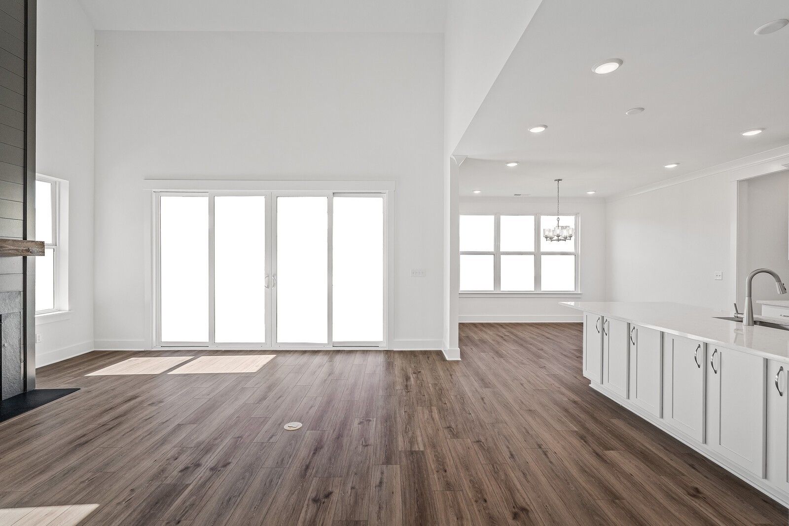 Open-concept great room with stone fireplace, sliding glass doors, and white kitchen island in Davidson Homes The Hawkins, Murfreesboro TN