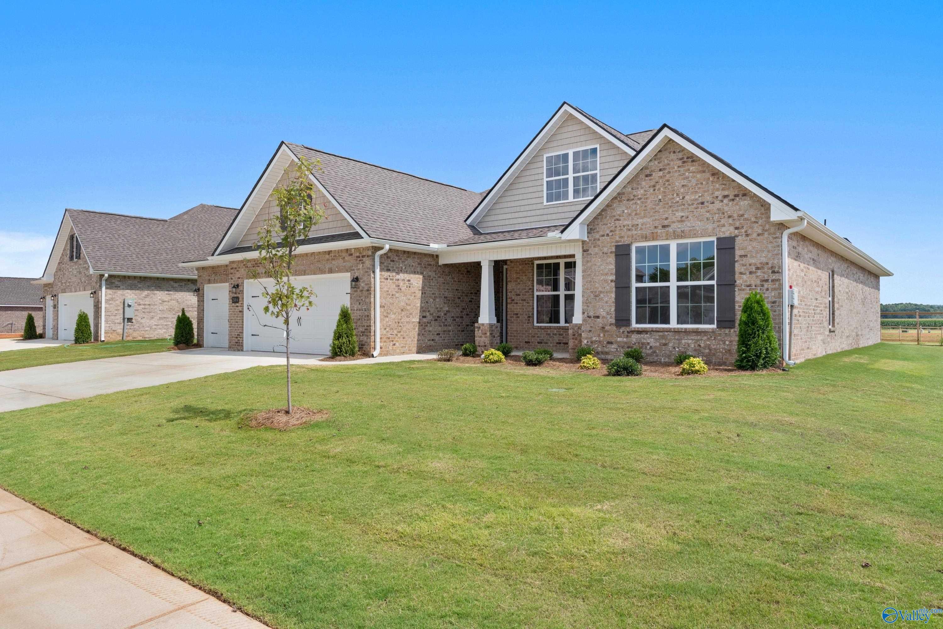 Brick single-story home with 3-car garage, gabled roof, columned porch, and manicured lawn in Kendall Farms, Toney, Alabama