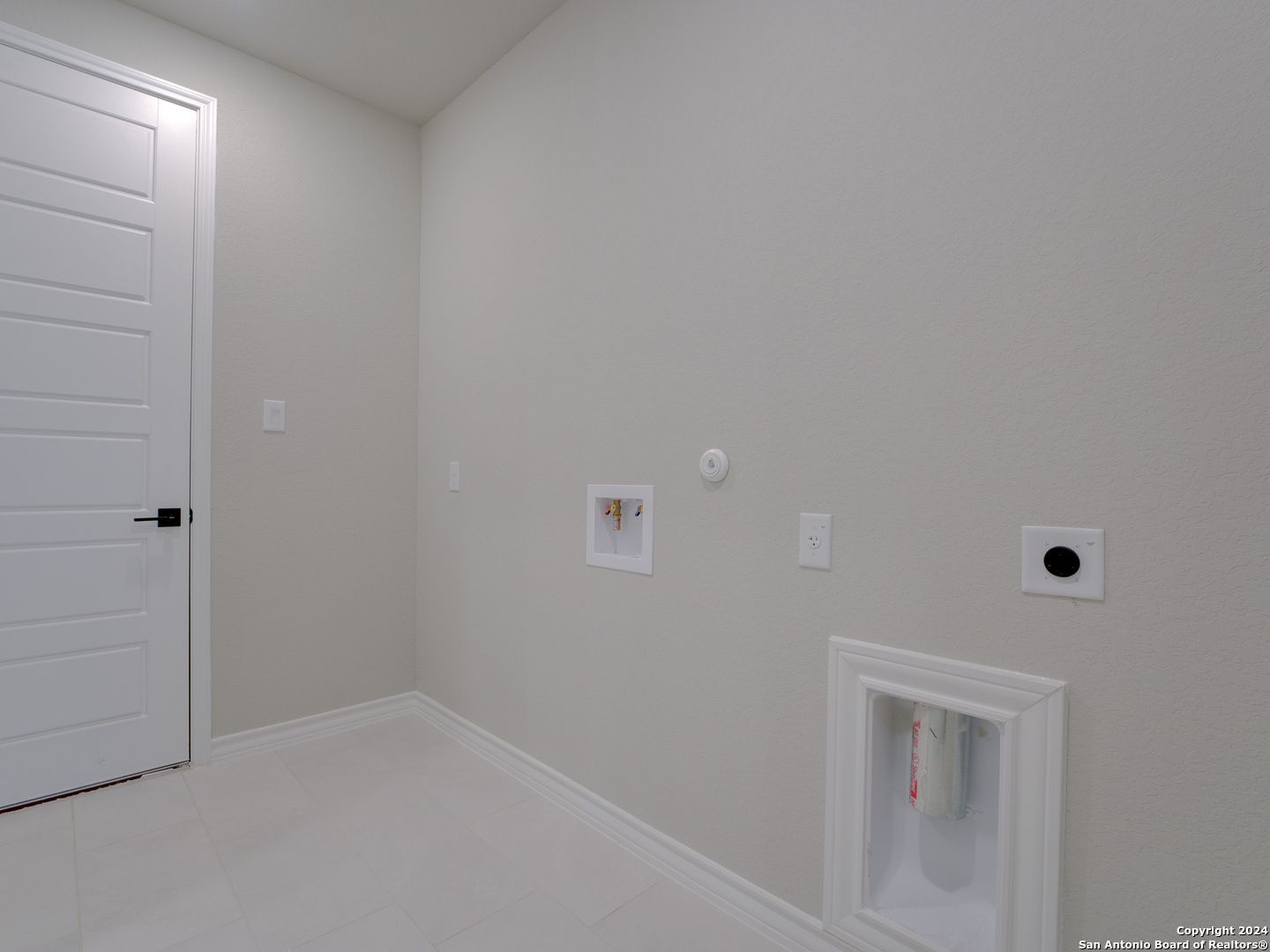 Modern laundry room featuring washer-dryer hookups, utility sink, and beige walls in The Summerlin A 4-bedroom home, Castroville, Texas