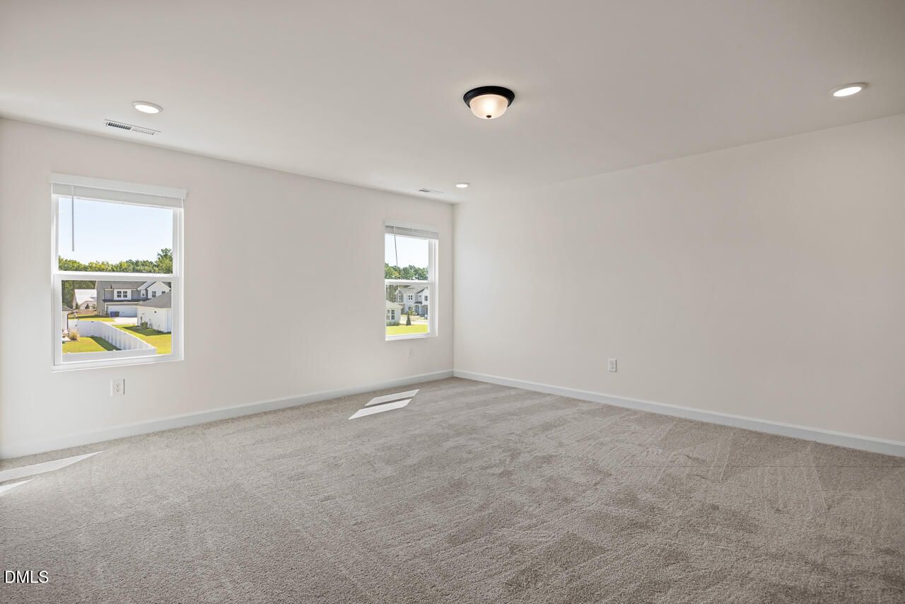 Bright spacious bedroom with carpet flooring and windows overlooking neighborhood in Davidson Homes Hickory II B, Lillington NC