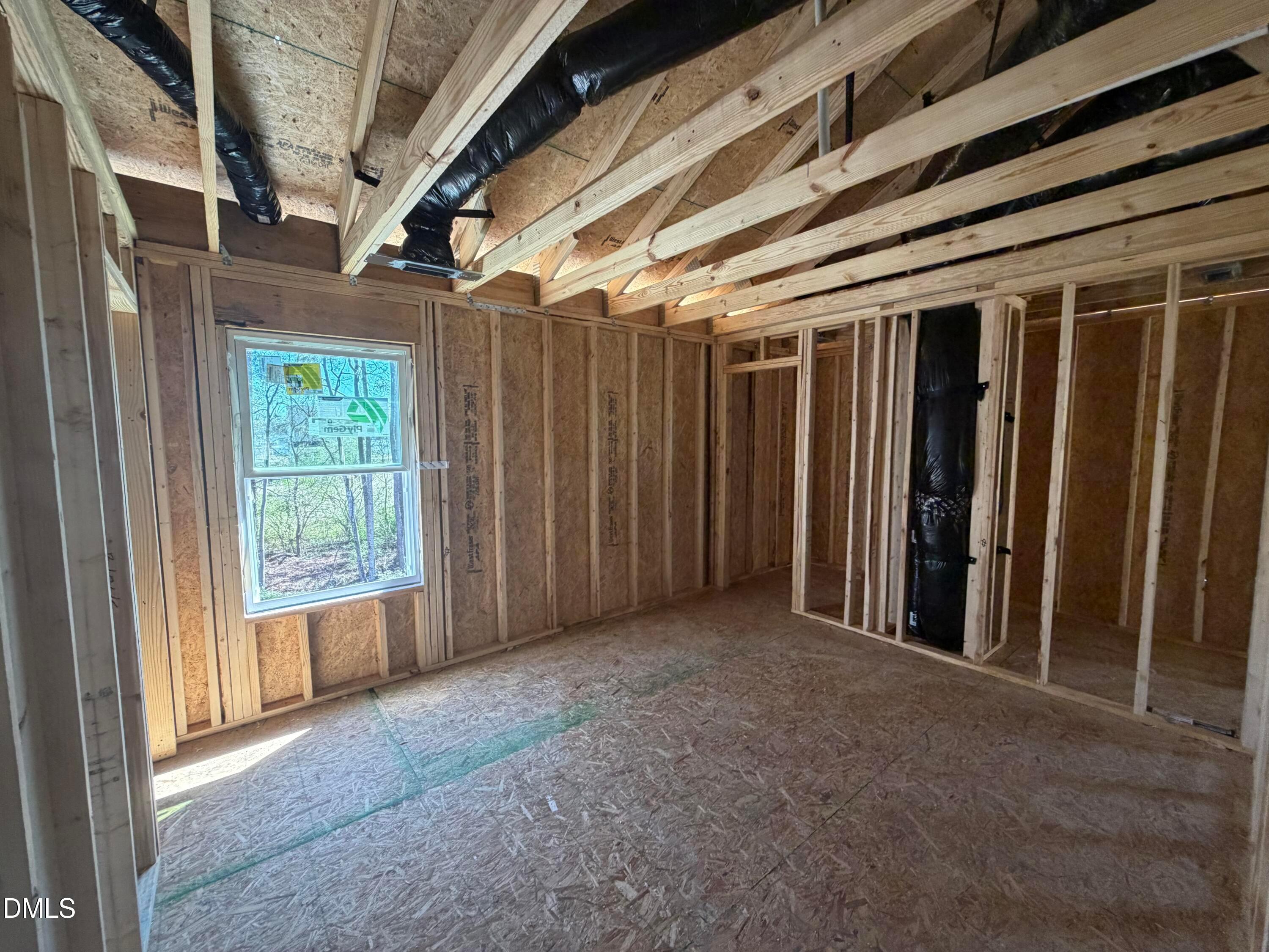 Wooden-framed bedroom with window overlooking greenery and exposed HVAC ducts in The Hickory II B, Lillington NC