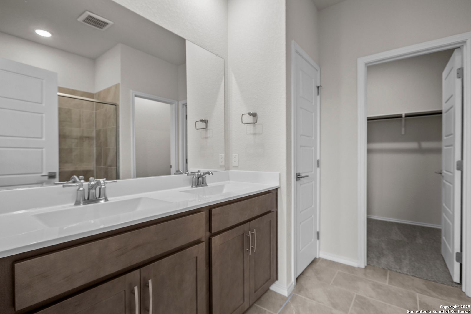 Modern master bathroom with double vanity, walk-in shower, and closet in Davidson Homes The Asheville J, San Antonio