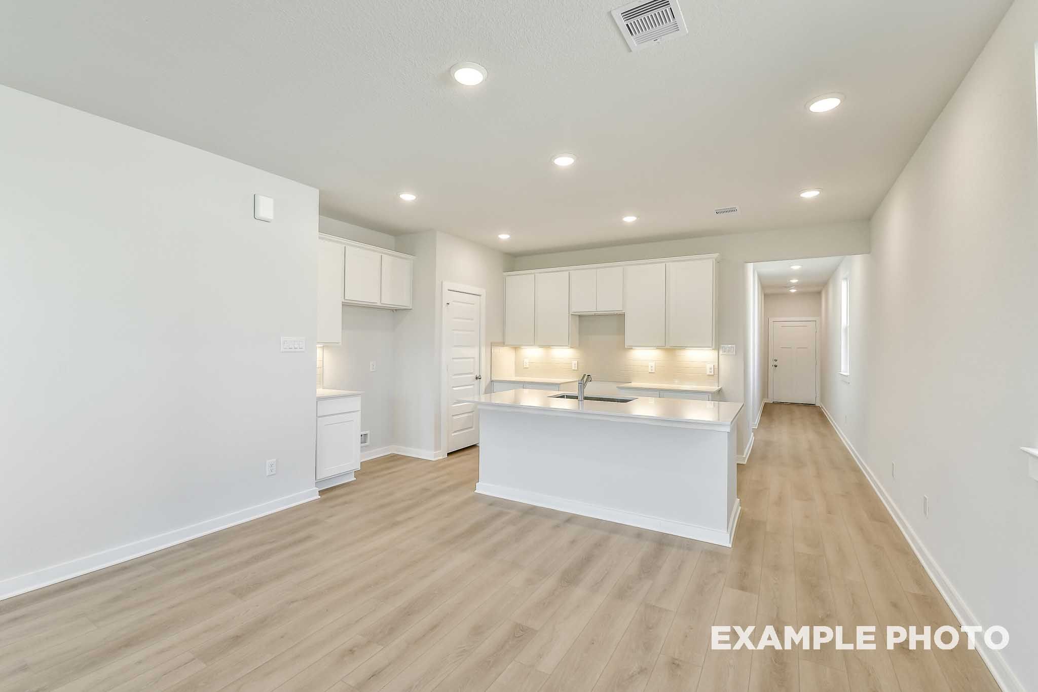 Bright open-concept kitchen with white cabinetry, large island, and luxury vinyl plank flooring in The Colorado by Davidson Homes.