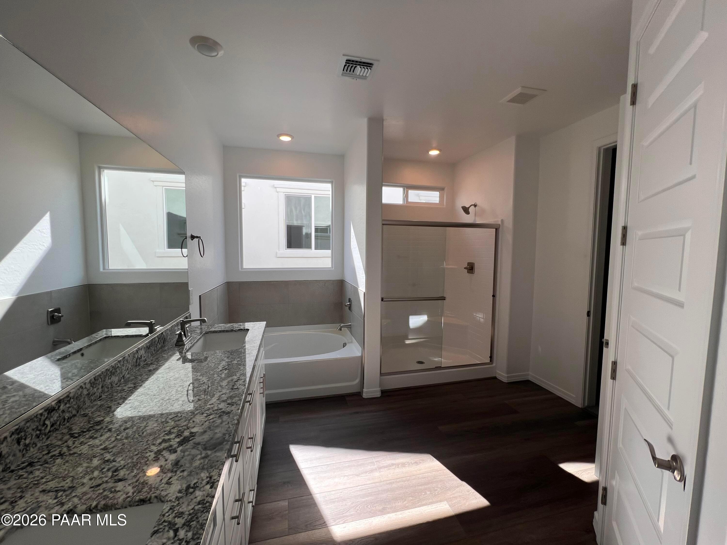 Luxurious master bathroom with double granite vanity, soaking tub, and frameless glass shower in Davidson Homes The Summit A, Prescott, AZ
