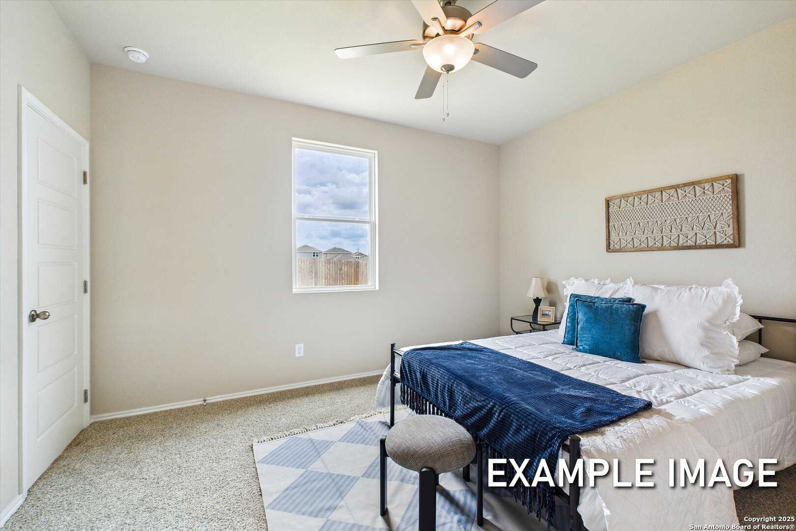 Cozy secondary bedroom with queen bed, blue bedding, ceiling fan, and window view in Davidson Homes The Comal B, Agave, San Antonio