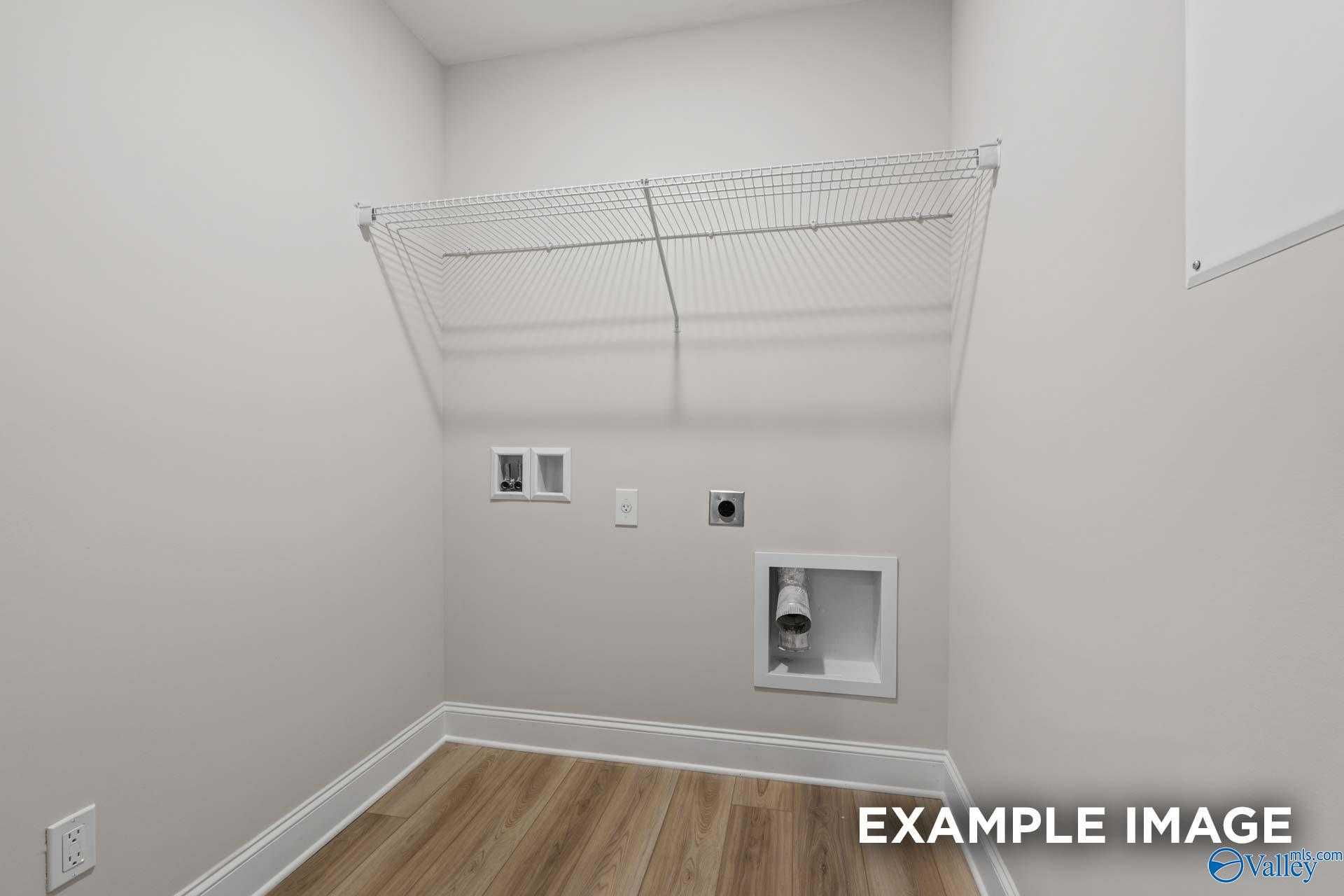 Bright laundry room with wire shelving, washer dryer hookups on white walls and hardwood floors in Davidson Homes The Camden D, Huntsville AL