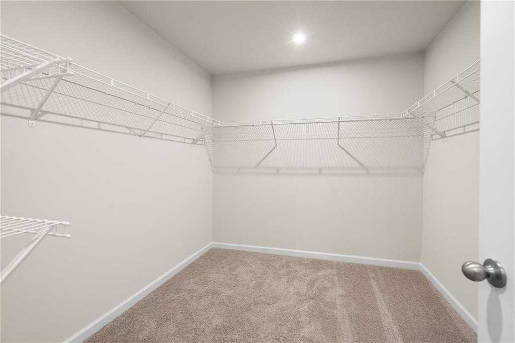Spacious walk-in closet with wire shelving and beige carpet in Davidson Homes The Marion B, Kennesaw, Georgia