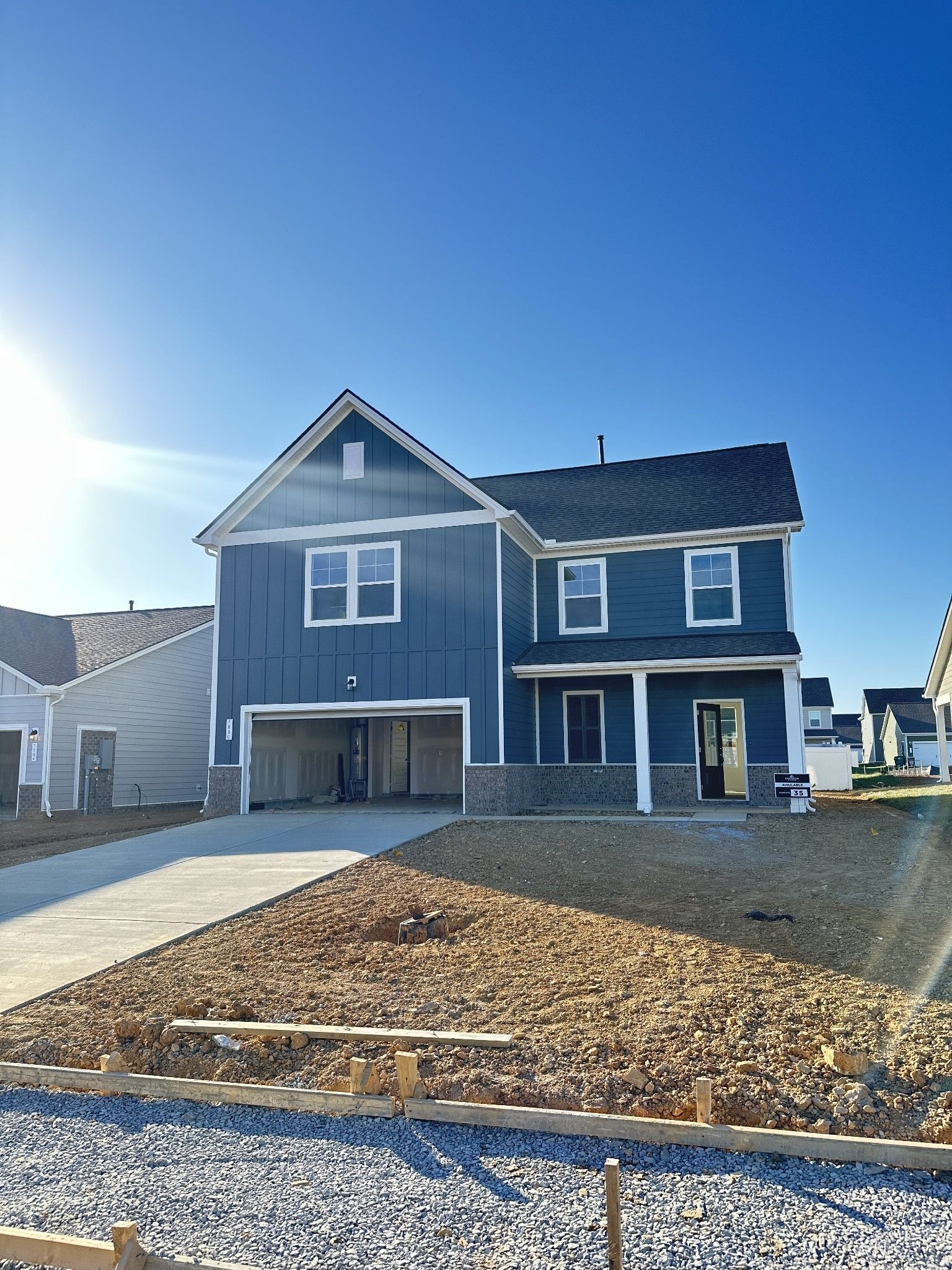 Modern blue two-story home with open 2-car garage, driveway, and front porch in Sage Farms, White House, Tennessee - Davidson Homes Gordon B