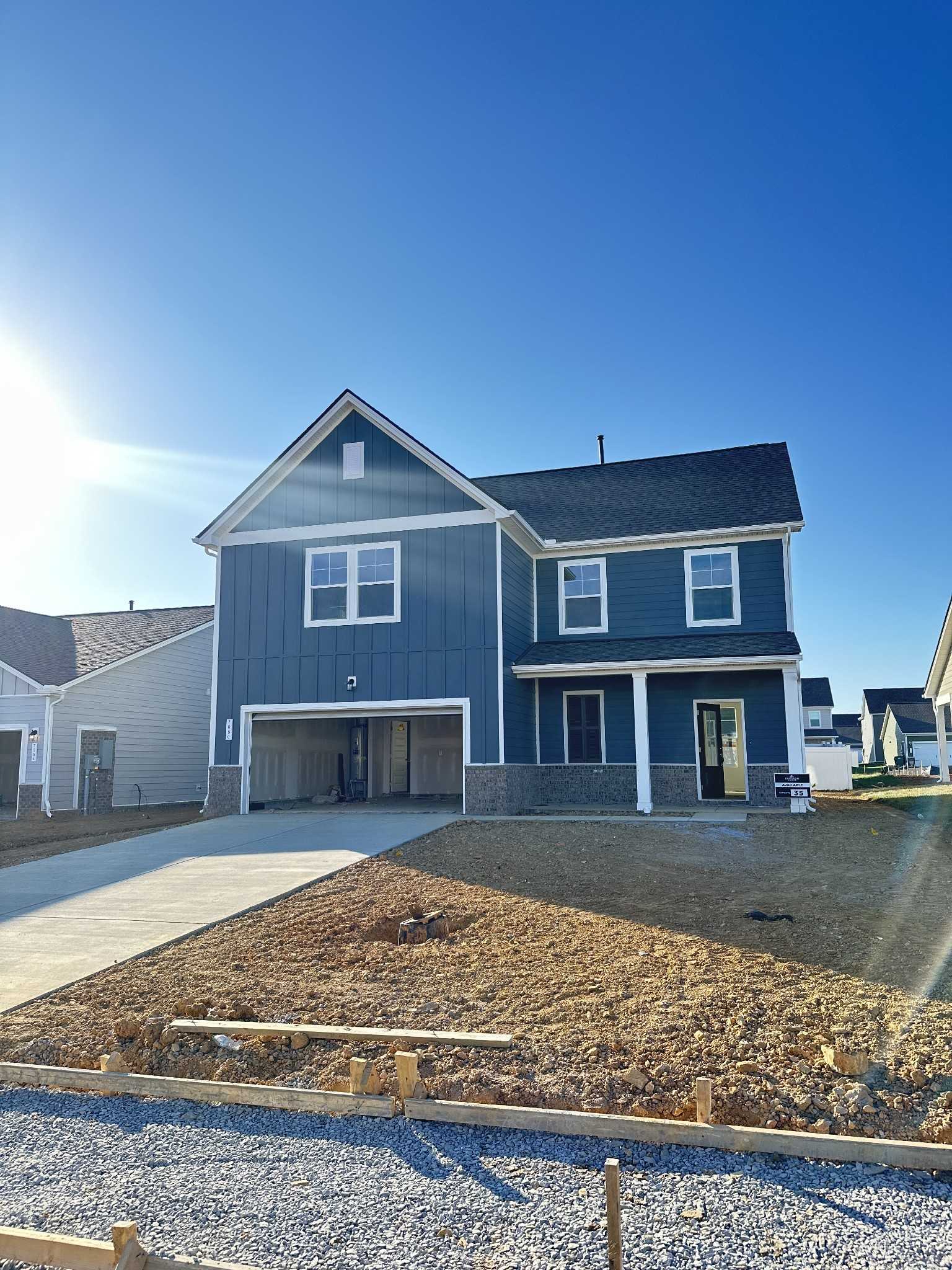 Modern blue two-story home with open 2-car garage, driveway, and front porch in Sage Farms, White House, Tennessee - Davidson Homes Gordon B