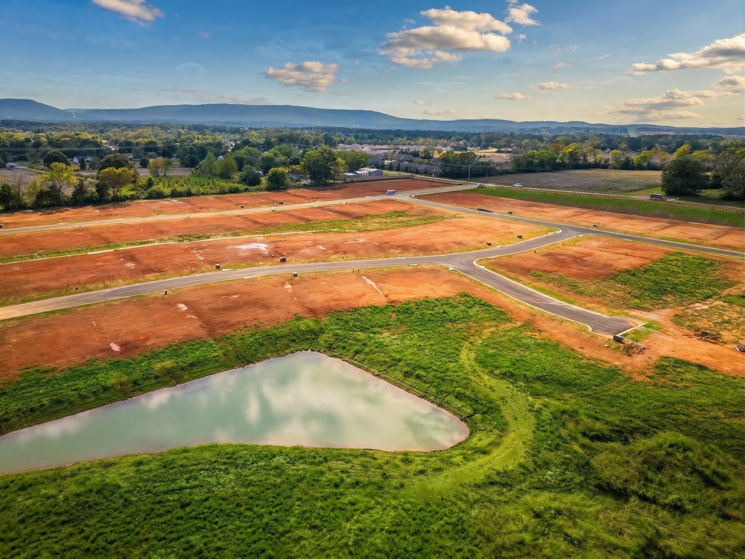 Aerial view of Berry Cove development in New Market Alabama featuring red dirt lots roads and pond by Davidson Homes