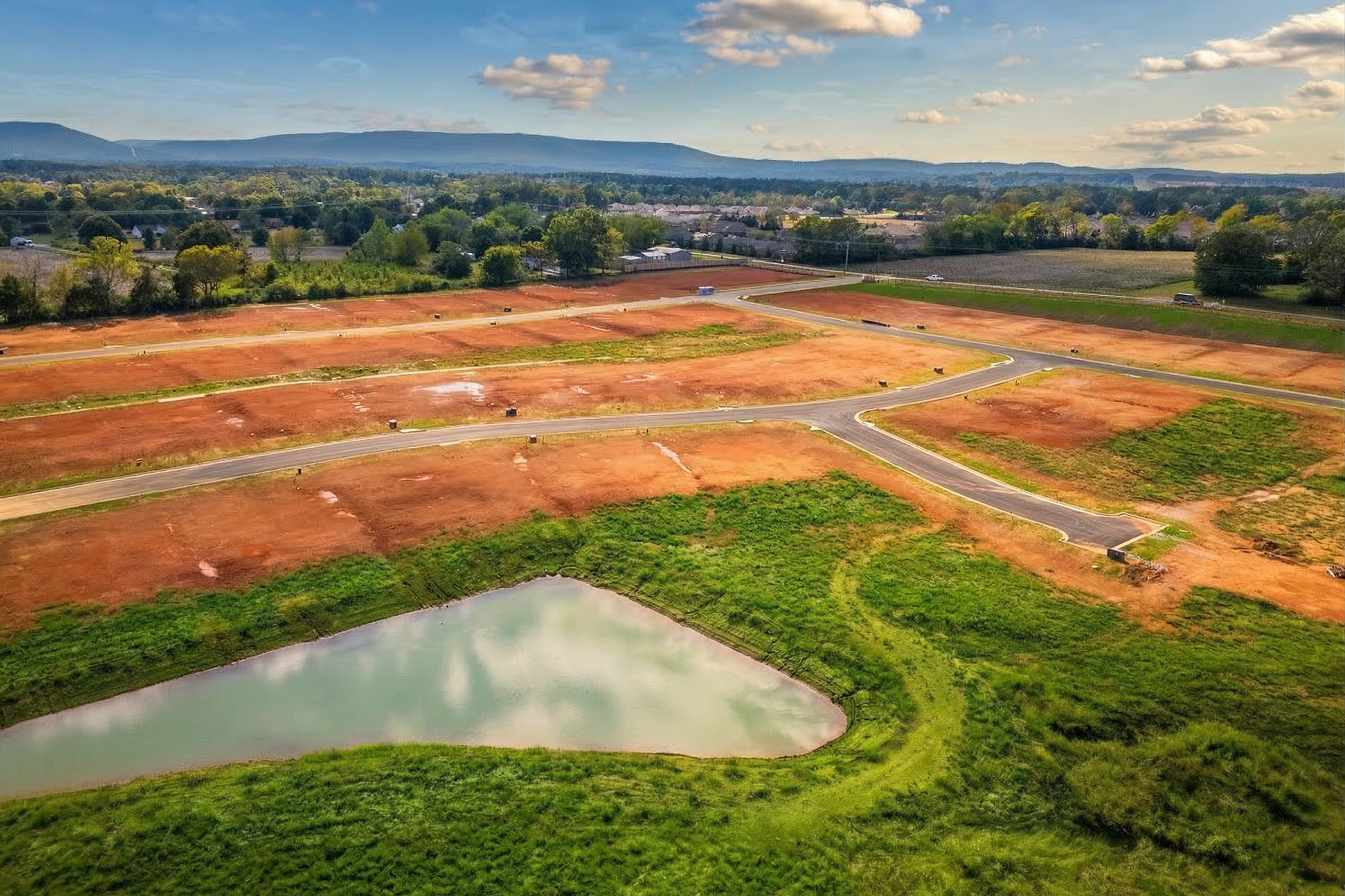 Aerial view of Berry Cove development in New Market Alabama featuring red dirt lots roads and pond by Davidson Homes