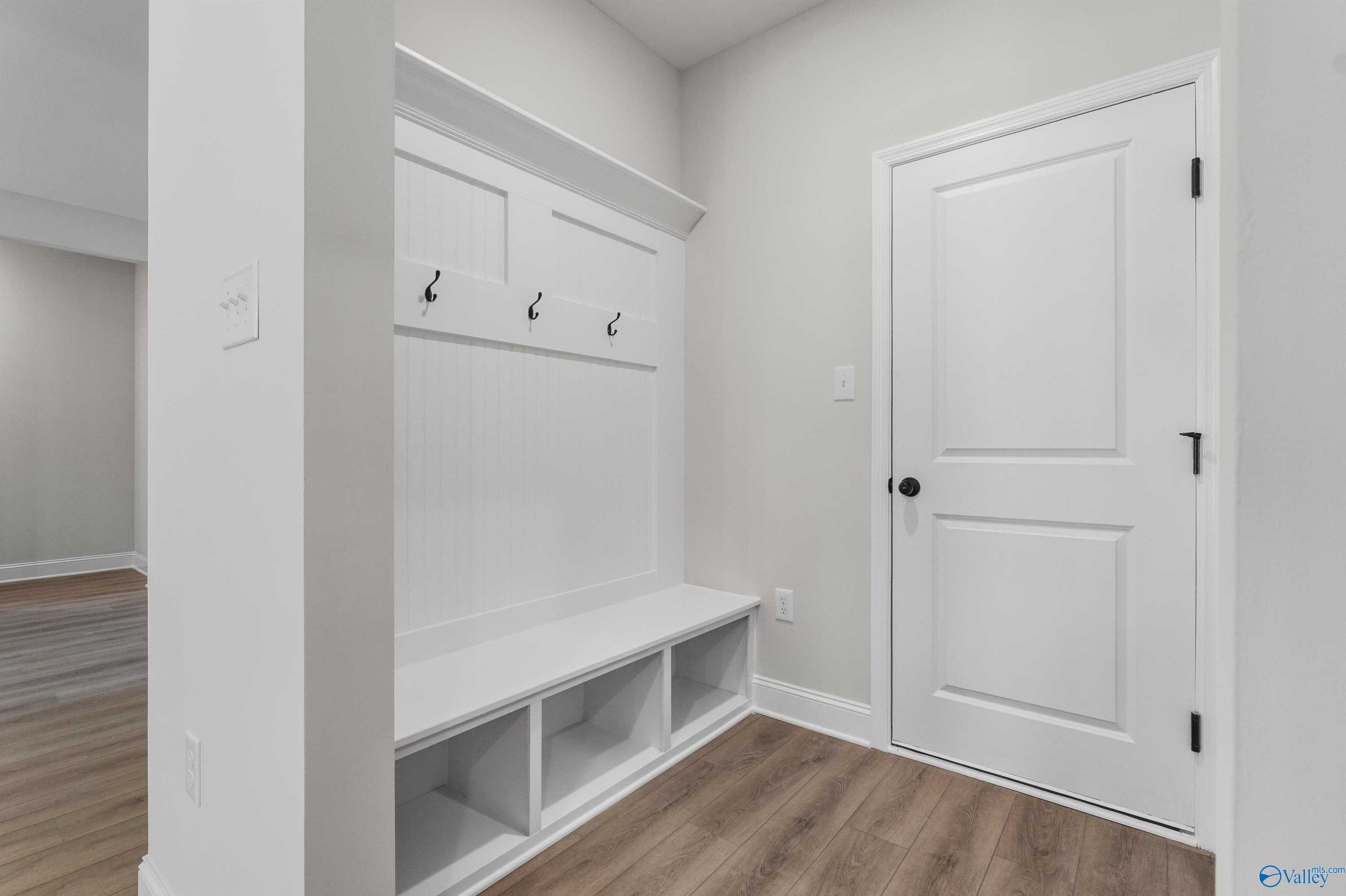 White mudroom with built-in bench, coat hooks, and storage cubbies in Davidson Homes The Montgomery C, Decatur, Alabama