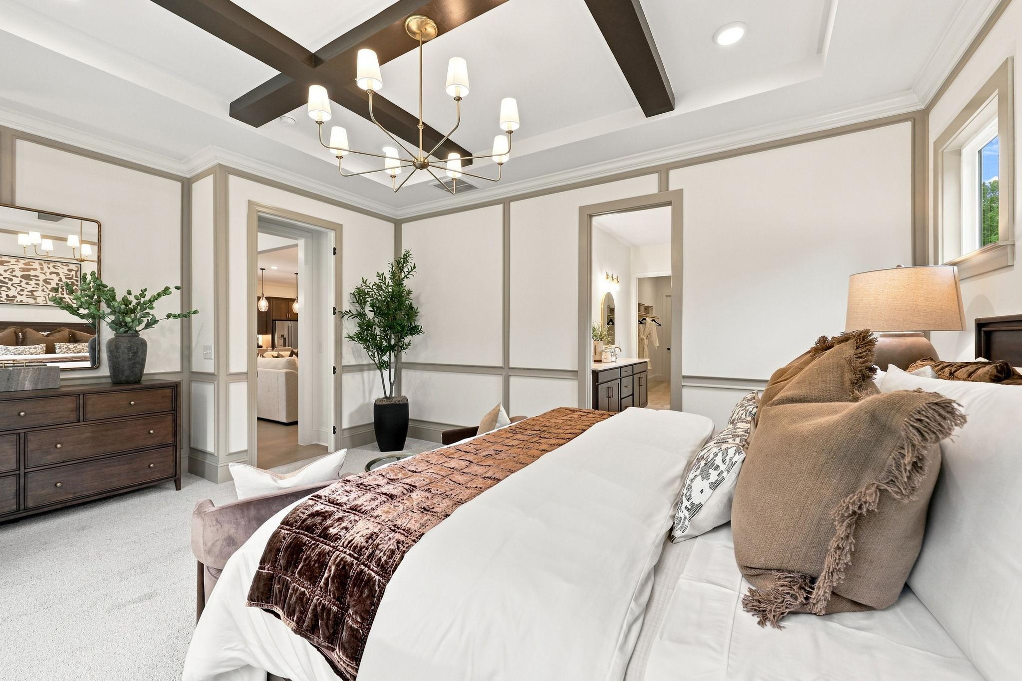 Spacious master suite on main floor of The Barrington C featuring coffered ceilings, elegant wall molding, and plush decor.