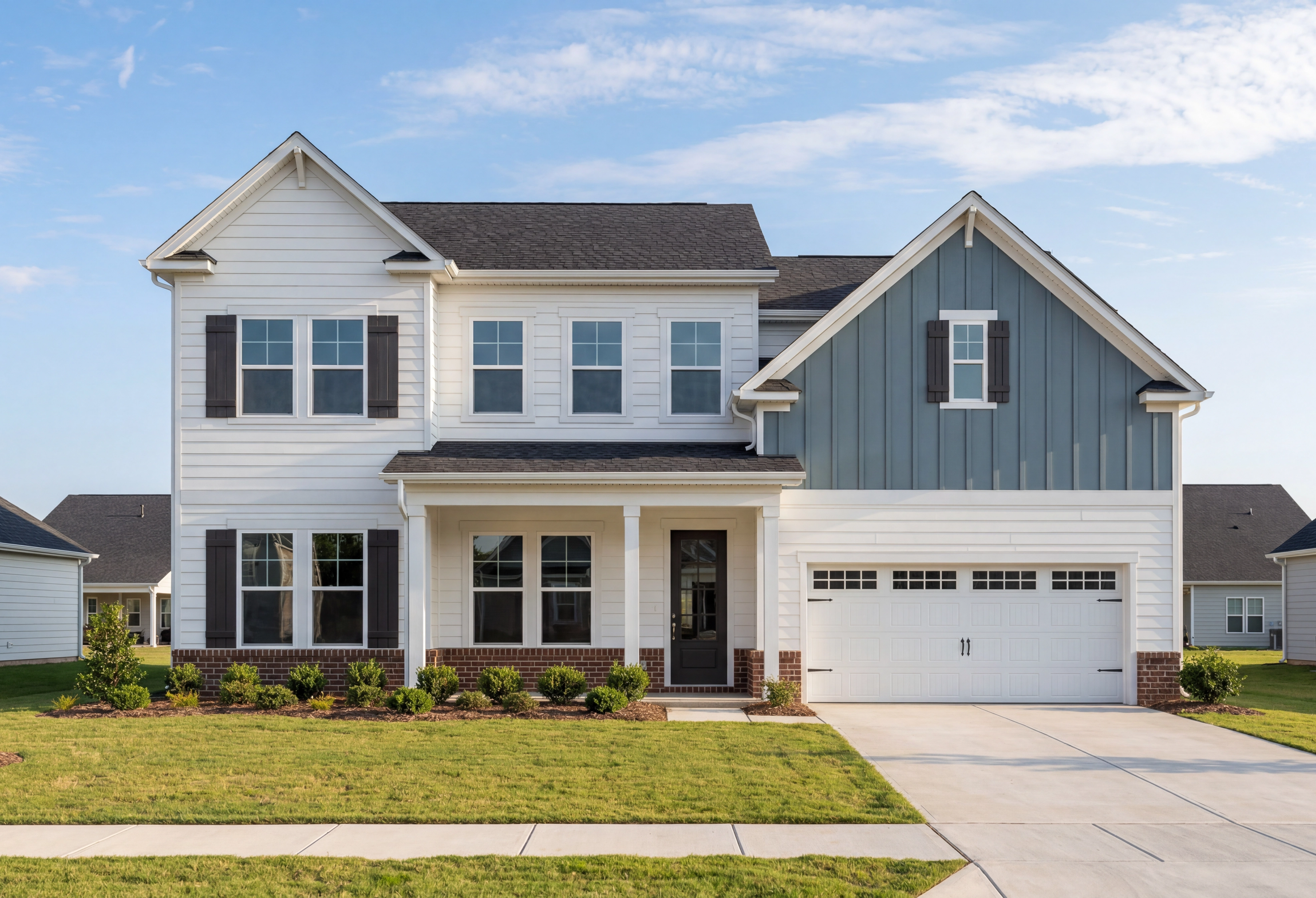 Two-story The Barrington A home elevation with white siding, gray gables, brick accents, covered porch, and two-car garage in Apex NC