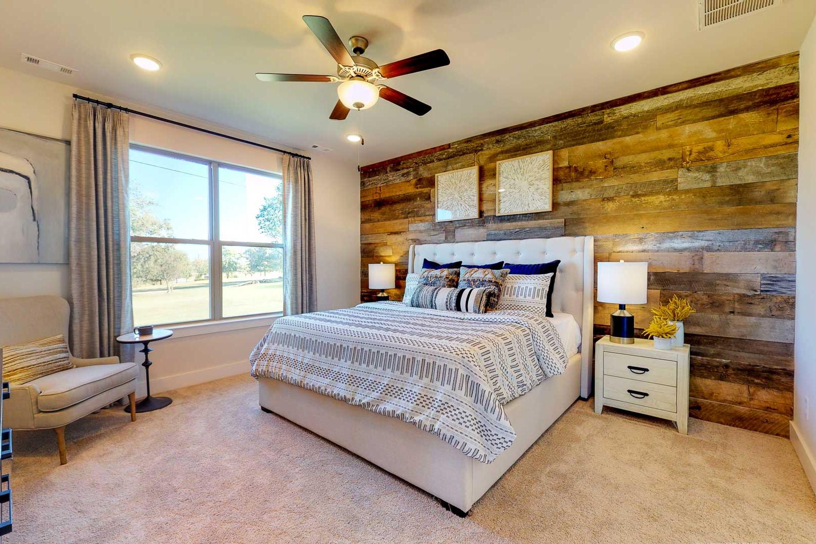 Spacious primary bedroom at Liberty Creek in Gallatin TN featuring rustic wood accent wall, king bed, and large windows