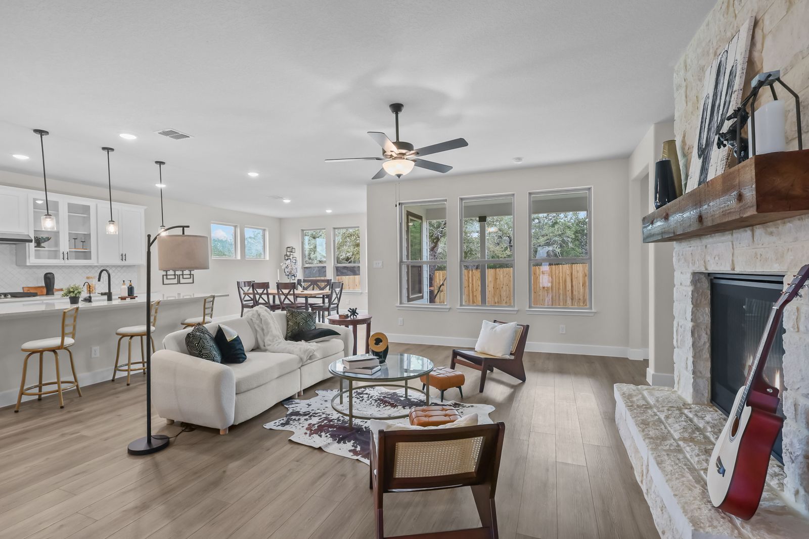Open-concept living room in The Belmont by Davidson Homes featuring a stone fireplace and spacious gourmet kitchen.