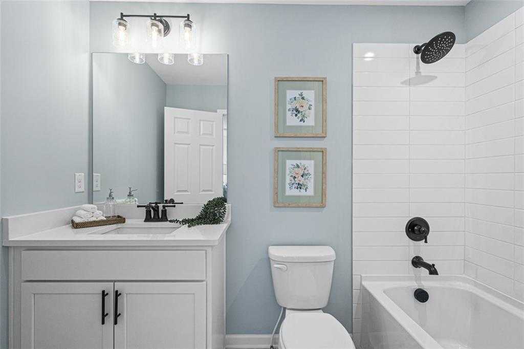 Elegant master bathroom with light blue walls, white shaker vanity, rainfall shower, soaking tub, and black fixtures in Davidson Homes The Hickory B, Hoschton, Georgia