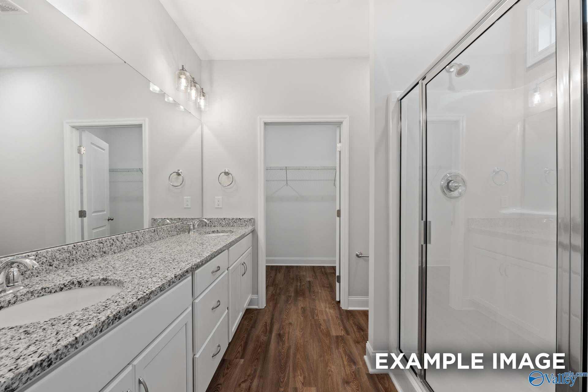 Modern master bathroom featuring double granite vanity, frameless walk-in shower, and hardwood floors in Davidson Homes The Cumberland, Decatur AL