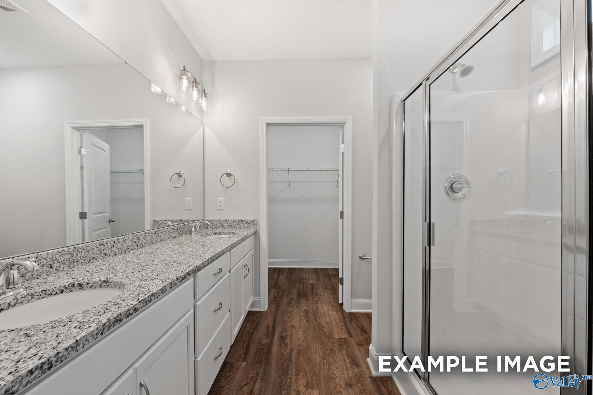 Modern master bathroom featuring double granite vanity, frameless glass shower, and walk-in closet in Davidson Homes The Cumberland, Decatur, Alabama