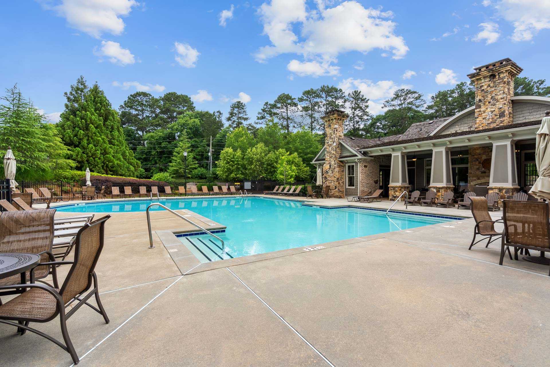 Resort-style swimming pool at The Village at Towne Lake in Woodstock Georgia with lounge chairs umbrellas and stone cabana