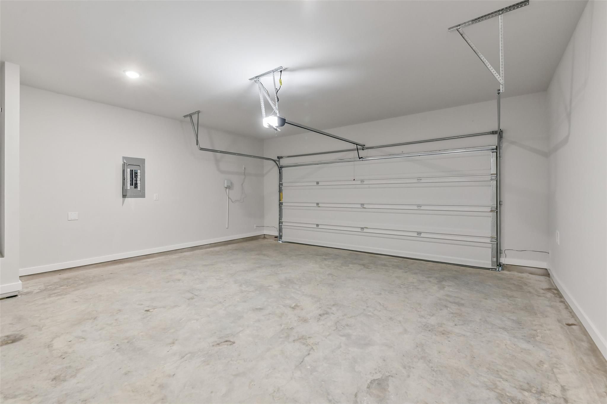 Spacious 2-car garage with concrete floor, white walls, and overhead door in Davidson Homes The Brazos E, Liberty Estates, Cleveland, Texas
