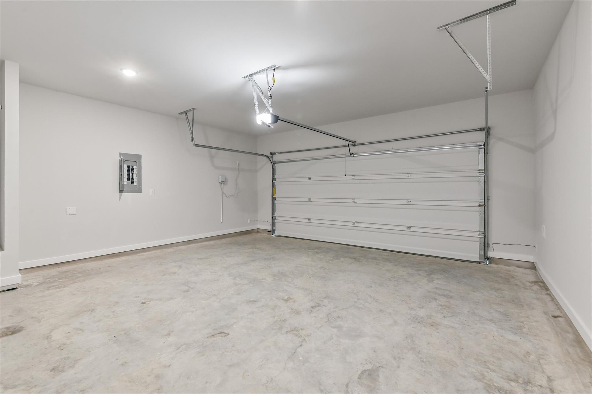 Spacious 2-car garage with concrete floor, white walls, and overhead door in Davidson Homes The Brazos E, Liberty Estates, Cleveland, Texas