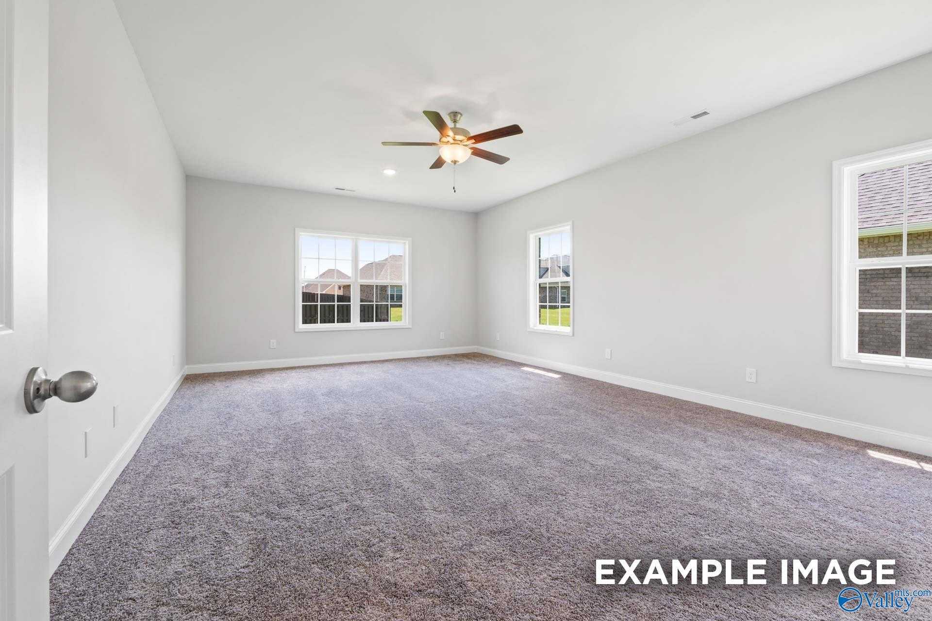 Empty bedroom featuring ceiling fan, large windows, and plush carpet in The Lanier 4-bedroom home by Davidson Homes, Meridianville, AL