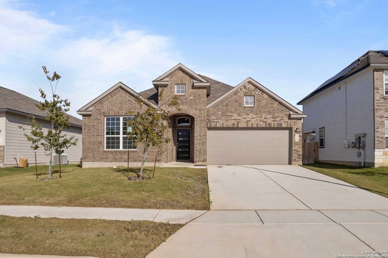 Modern brick single-story home with gabled roof, 2-car garage, arched door, and landscaped yard in Hannah Heights, Seguin, Texas