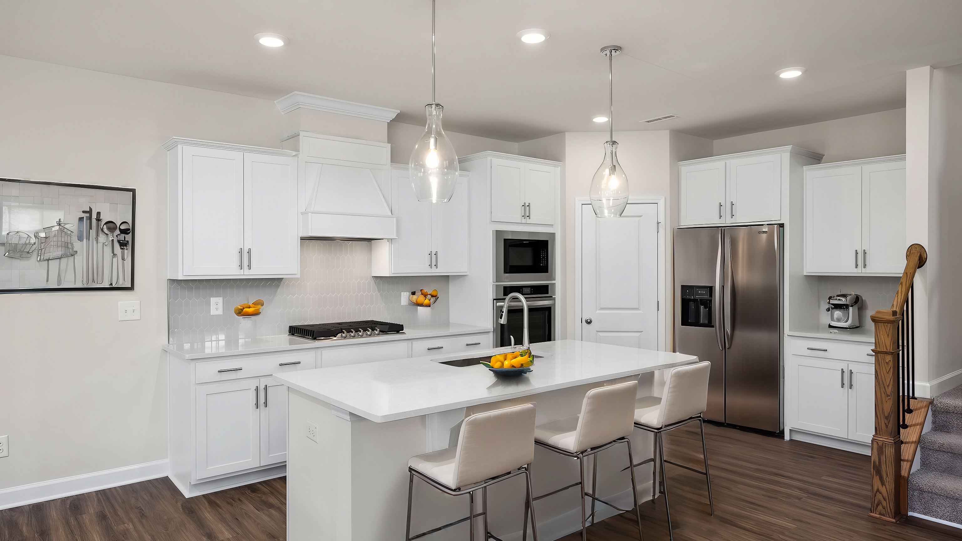 Spacious white kitchen with quartz island, bar stools, stainless appliances at Wendell Ridge, Wendell NC by Davidson Homes