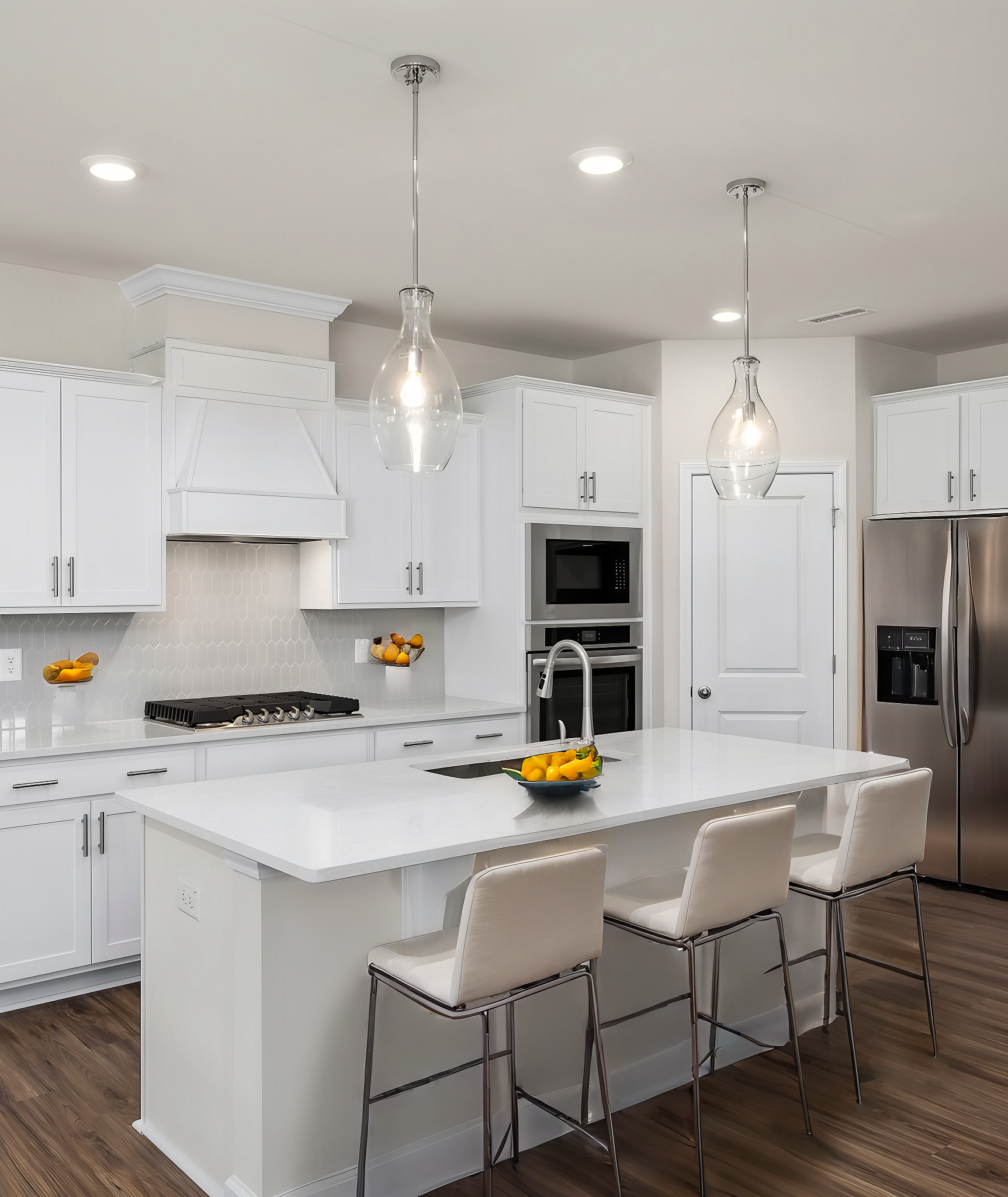 Spacious white kitchen with quartz island, bar stools, stainless appliances at Wendell Ridge, Wendell NC by Davidson Homes