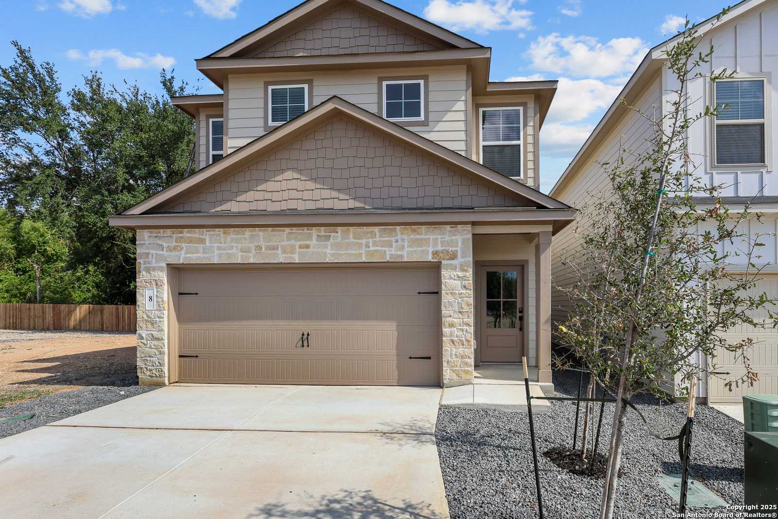 Modern two-story beige home with stone facade, two-car garage, and landscaped driveway in Cedar Heights, San Antonio, Texas - Davidson Homes The Charlotte B