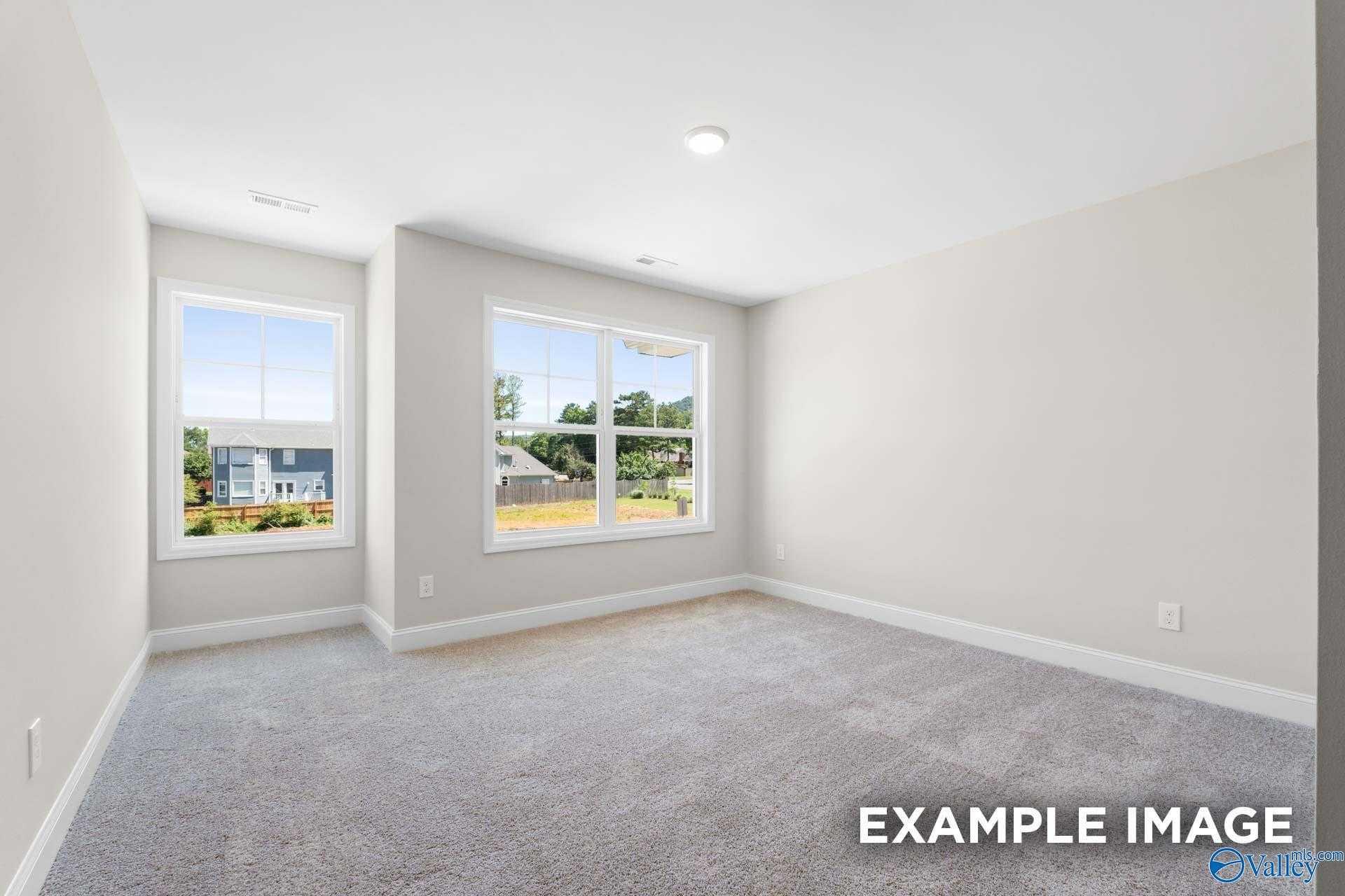 Bright secondary bedroom with large windows overlooking green backyard in The Camden C by Davidson Homes, Huntsville, Alabama