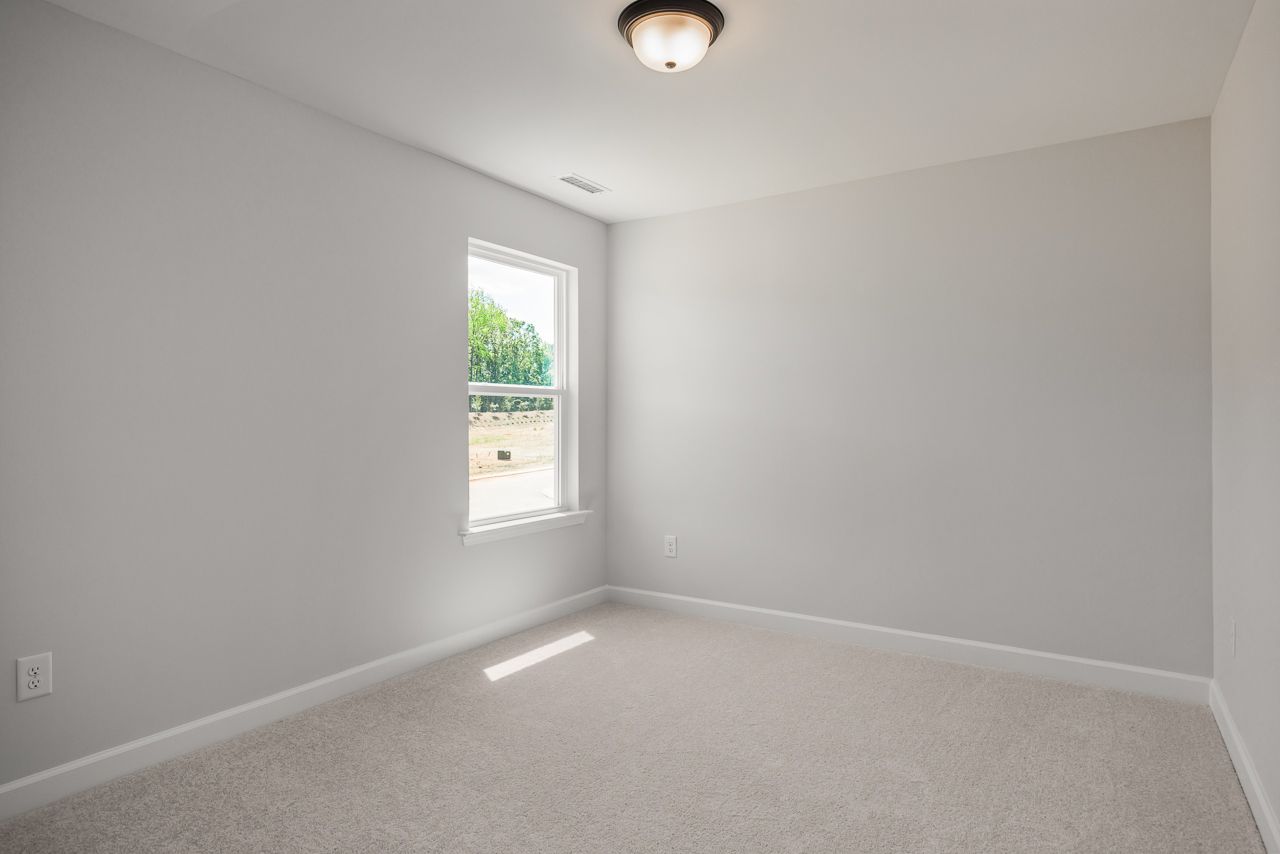 Bright, neutral-toned bedroom in The Birch II D floor plan by Davidson Homes with plush carpeting and natural light.