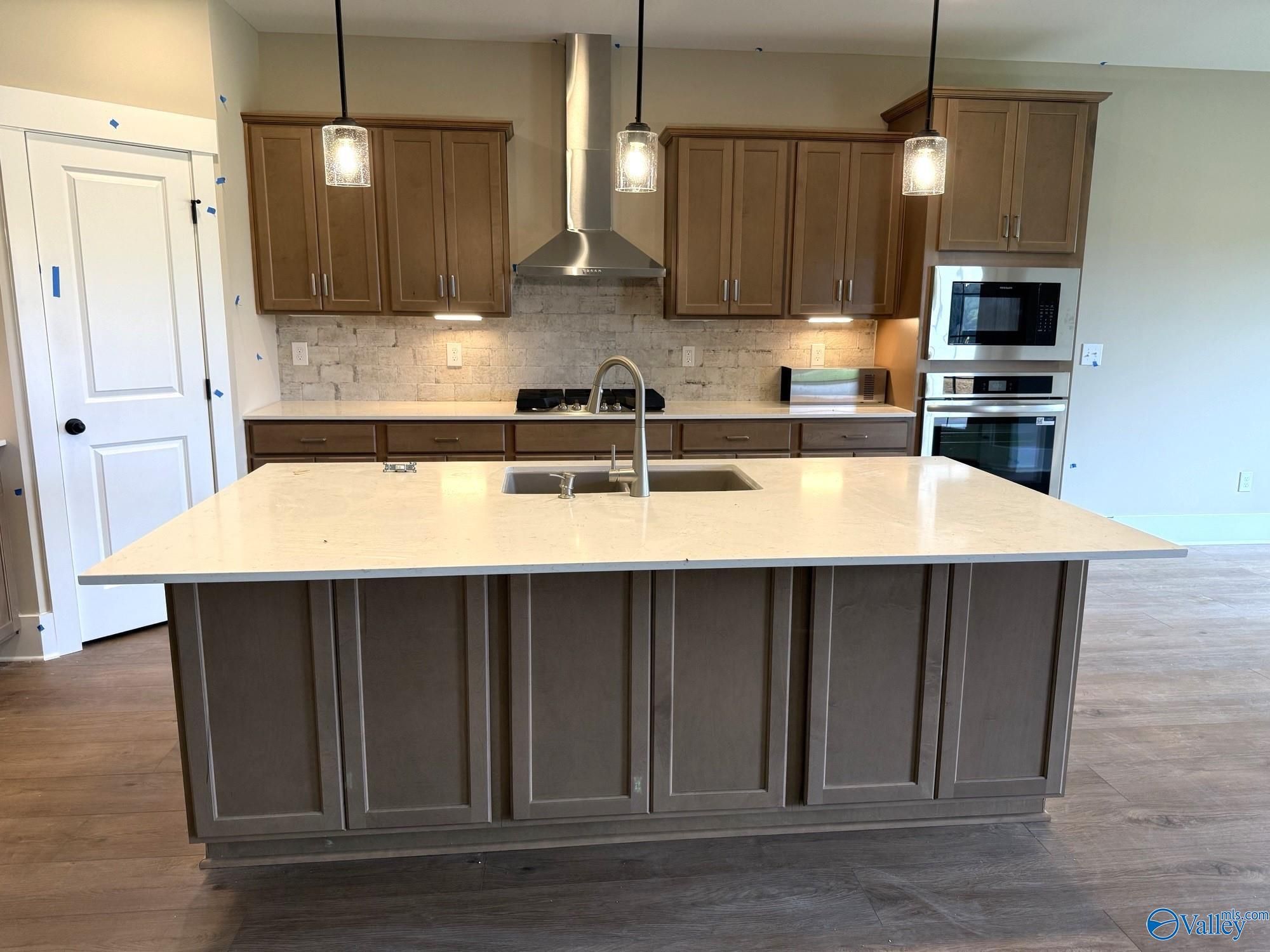 Modern kitchen with large island, stainless steel appliances, and wood cabinets in The Rockford floor plan, Cain Park.
