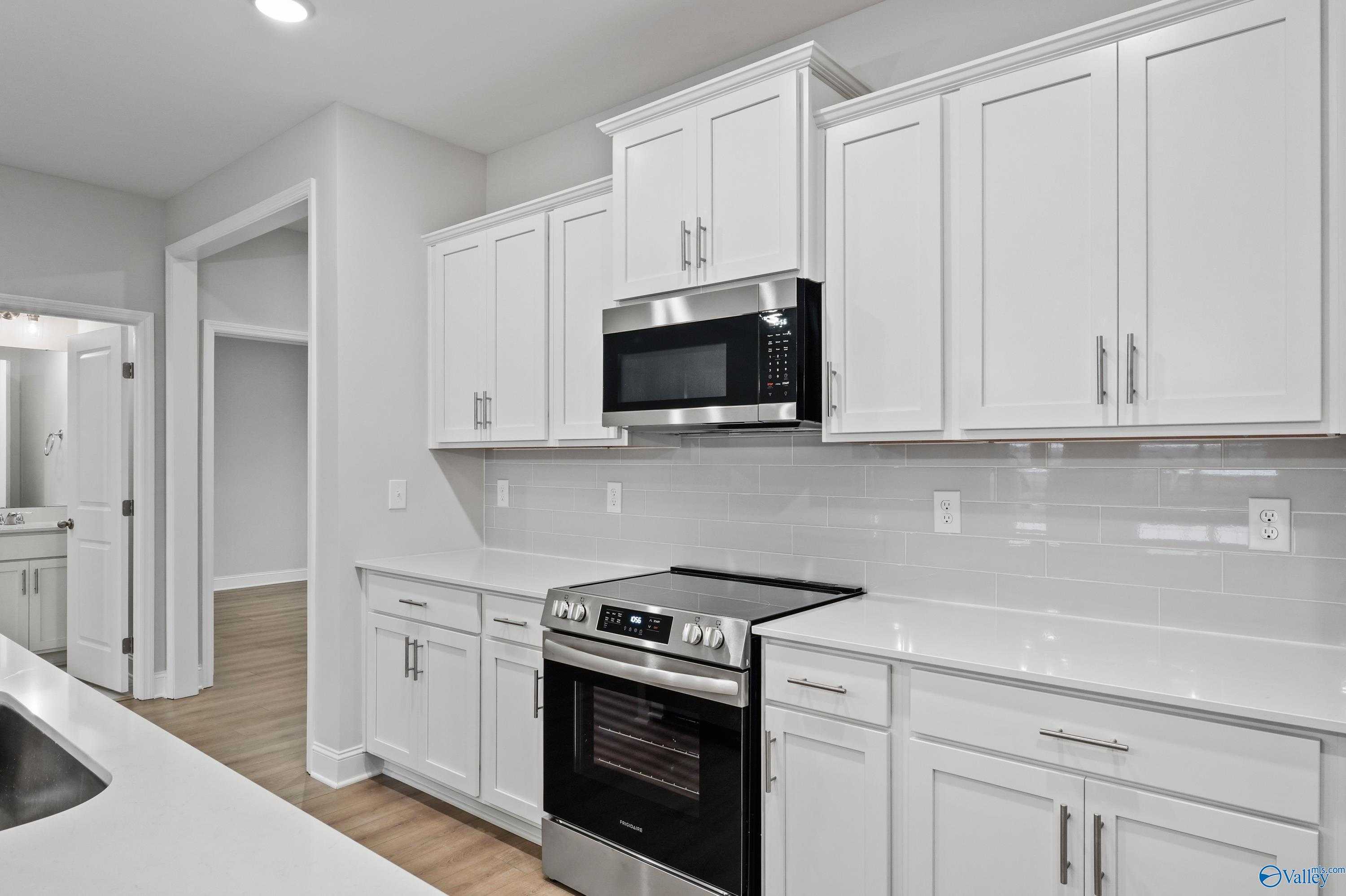Bright kitchen with white cabinets, stainless steel appliances, subway tile backsplash in The Lanier by Davidson Homes, Harvest AL