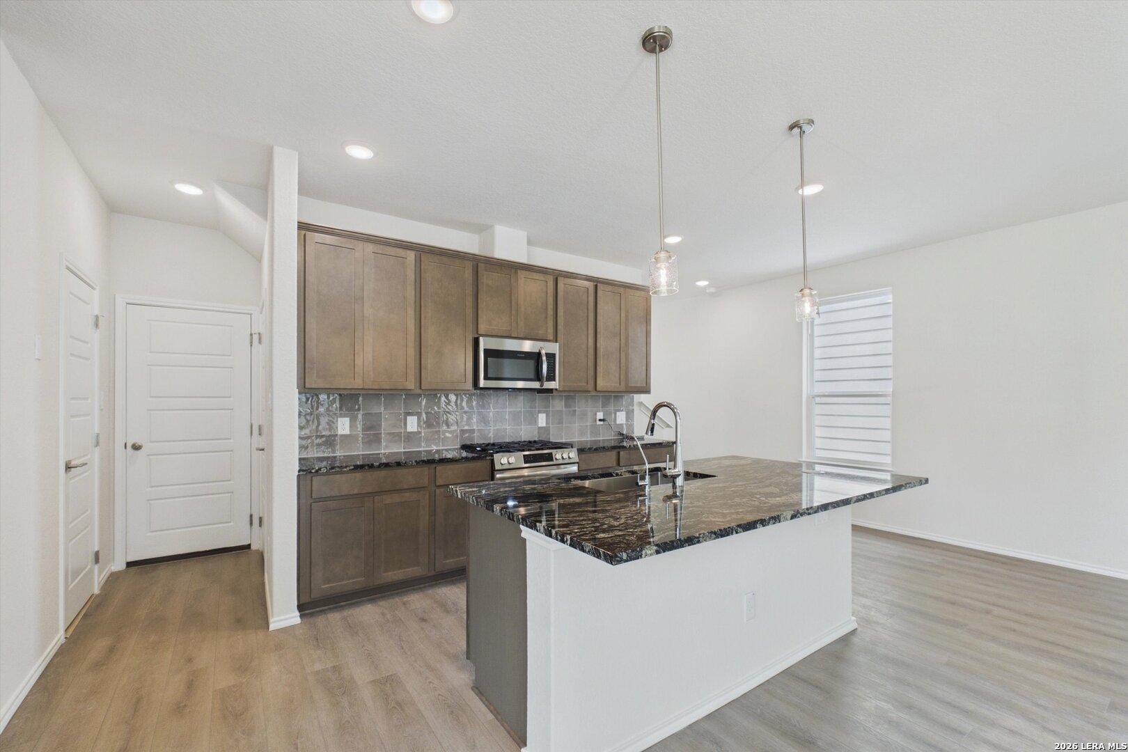 Modern kitchen with granite countertops, island, and wood cabinets in The Charlotte B floor plan, Meadows at Oak Creek.
