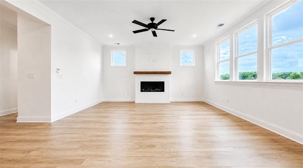 Bright living room with fireplace and wood floors in The Hickory C floor plan at Wehunt Meadows, Hoschton, Georgia.