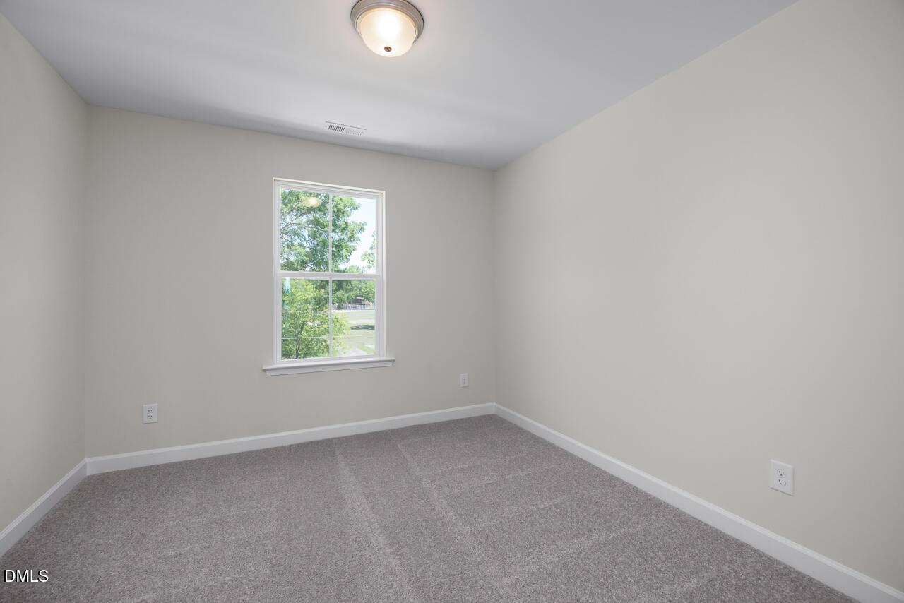Bright, neutral-toned bedroom with plush carpet in The Mitchell floor plan at Camden Park, Knightdale, North Carolina.