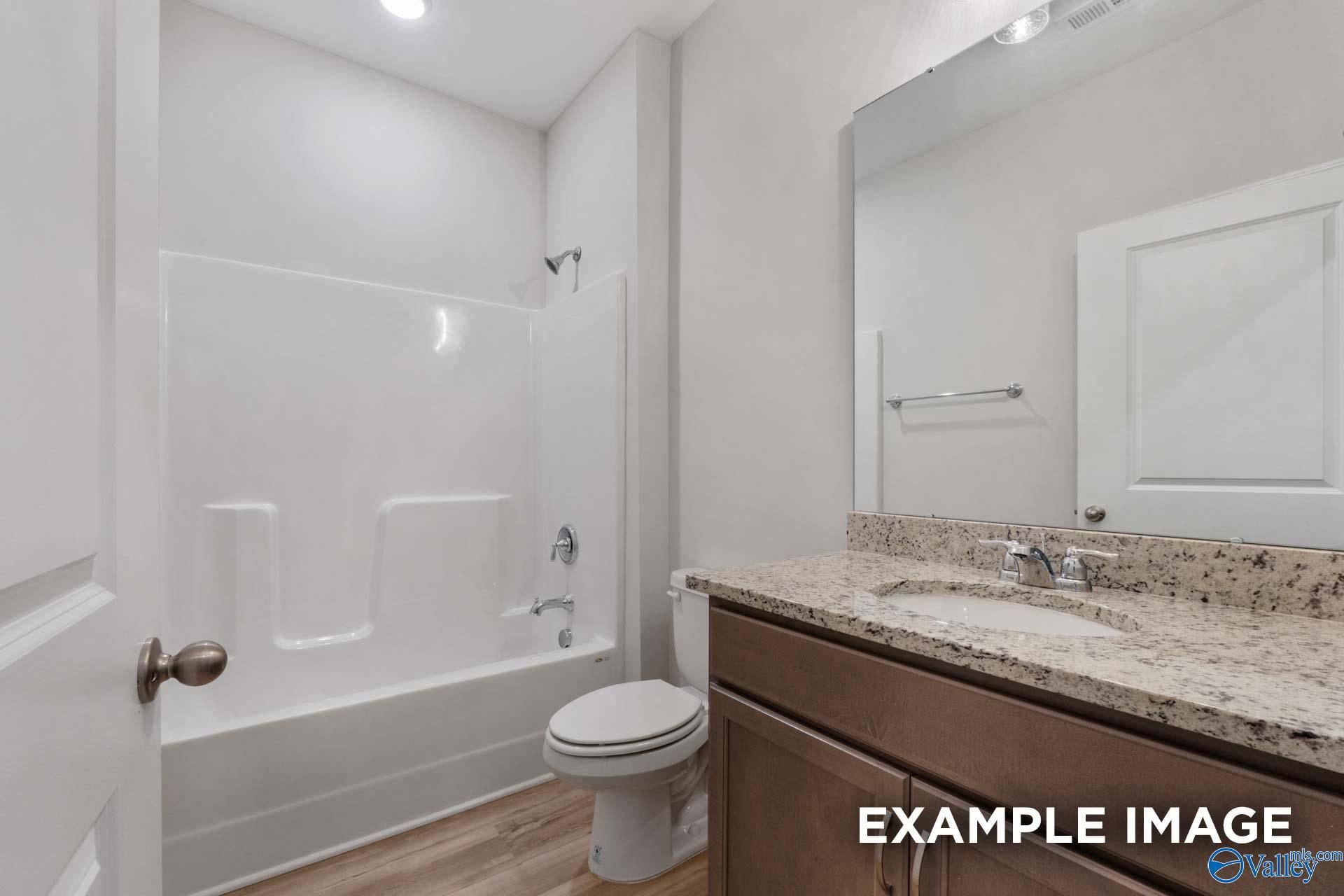 Modern guest bathroom featuring tub-shower combo, granite vanity, and wood cabinets in Davidson Homes The Cumberland B, Decatur, AL