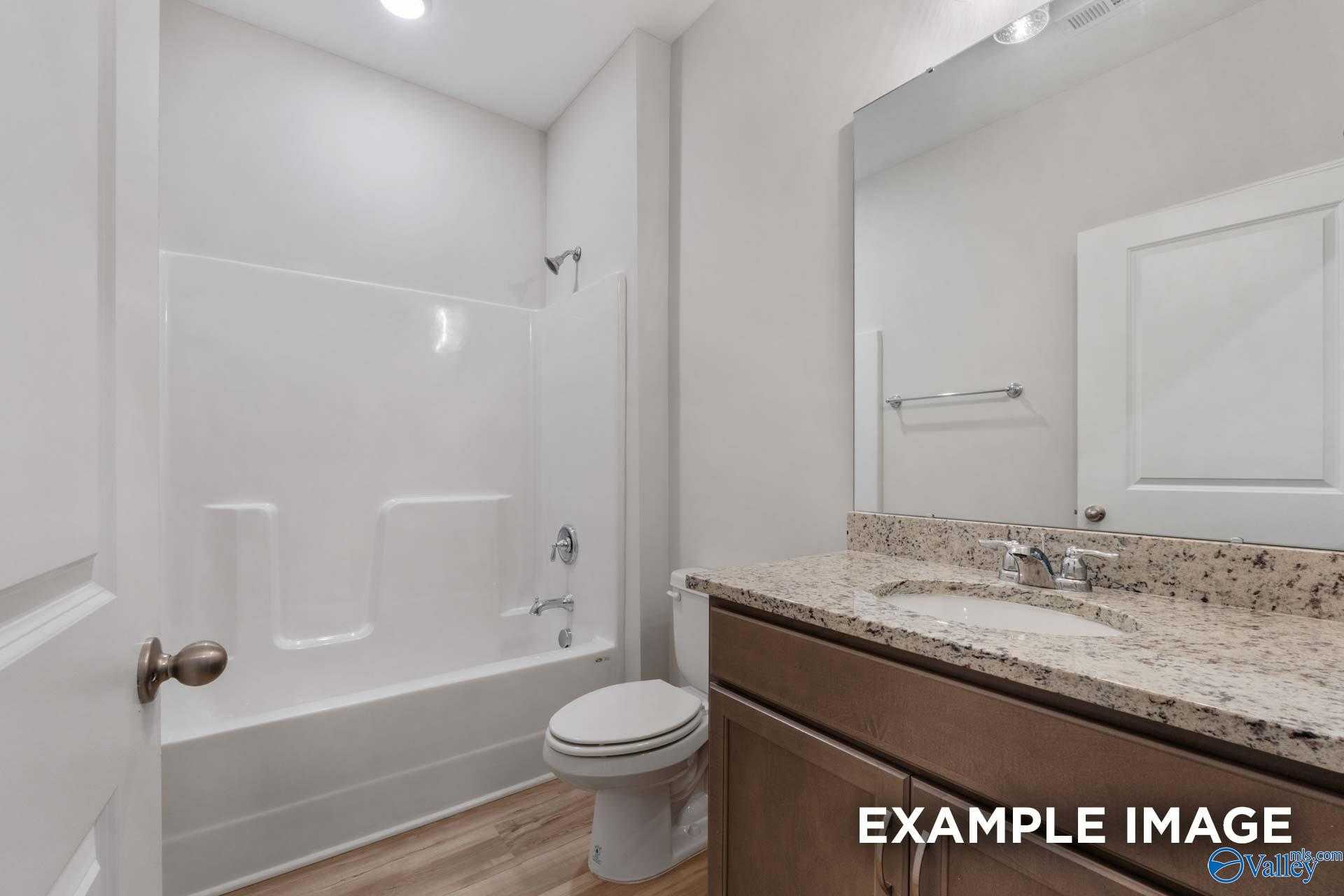 Modern guest bathroom featuring tub-shower combo, granite vanity, and wood cabinets in Davidson Homes The Cumberland B, Decatur, AL
