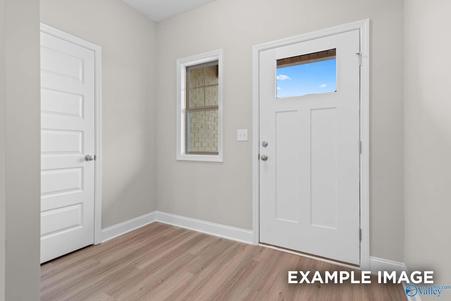 Bright entryway with light wood-style flooring and white front door in The Camilla C floor plan at The Retreat, Hartselle.
