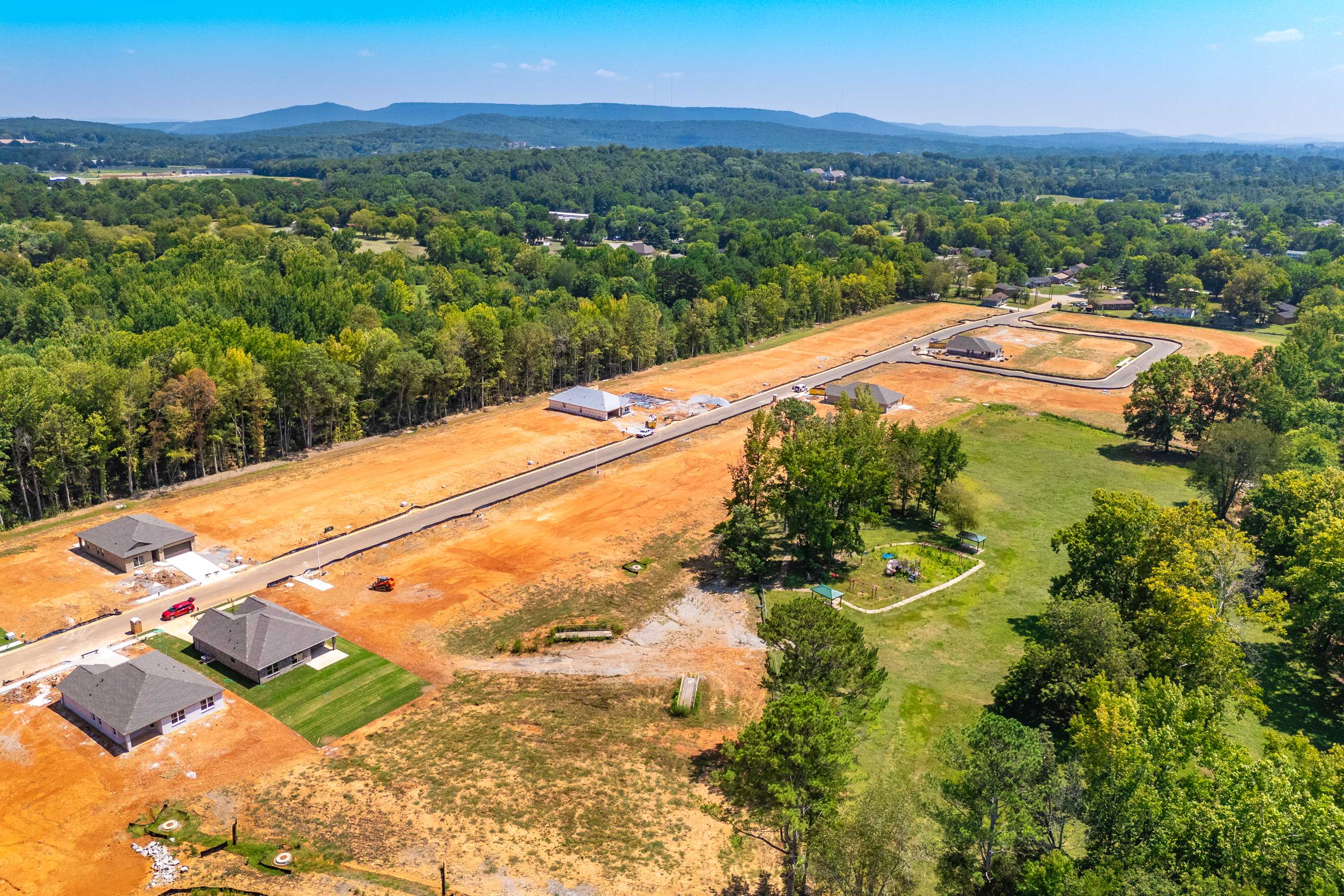Aerial view of Spragins Cove construction in Huntsville AL with new homes, dirt roads, and wooded hills by Davidson Homes