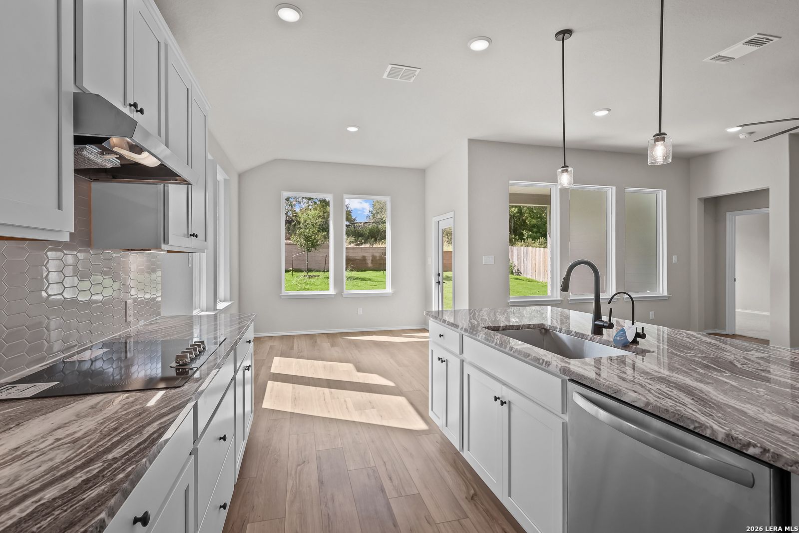 Bright kitchen with white cabinetry, granite island, and hexagon tile backsplash in Davidson Homes' The Sequoia C, Royal Crest, San Antonio